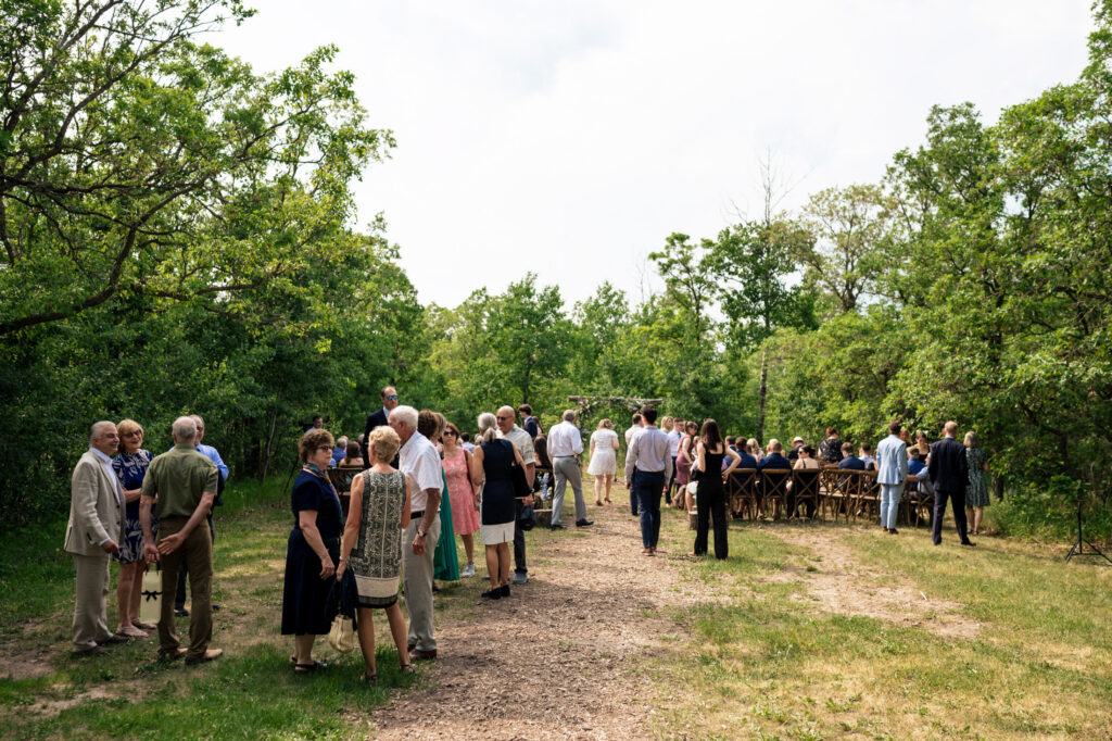 A group of people gathered outside among trees on a sunny day.