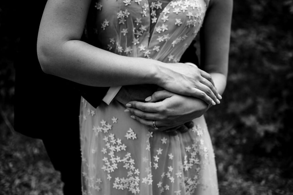 Couple embracing; woman's dress adorned with floral details. Black and white image.