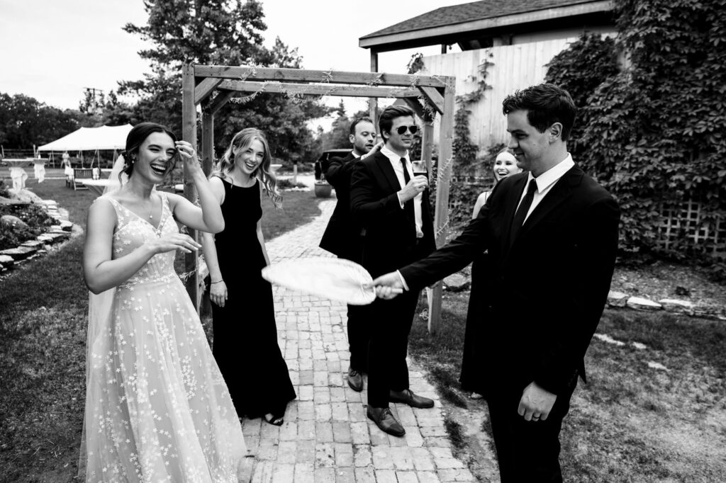 Wedding party in black and white, two men playing with a handkerchief, others laughing.