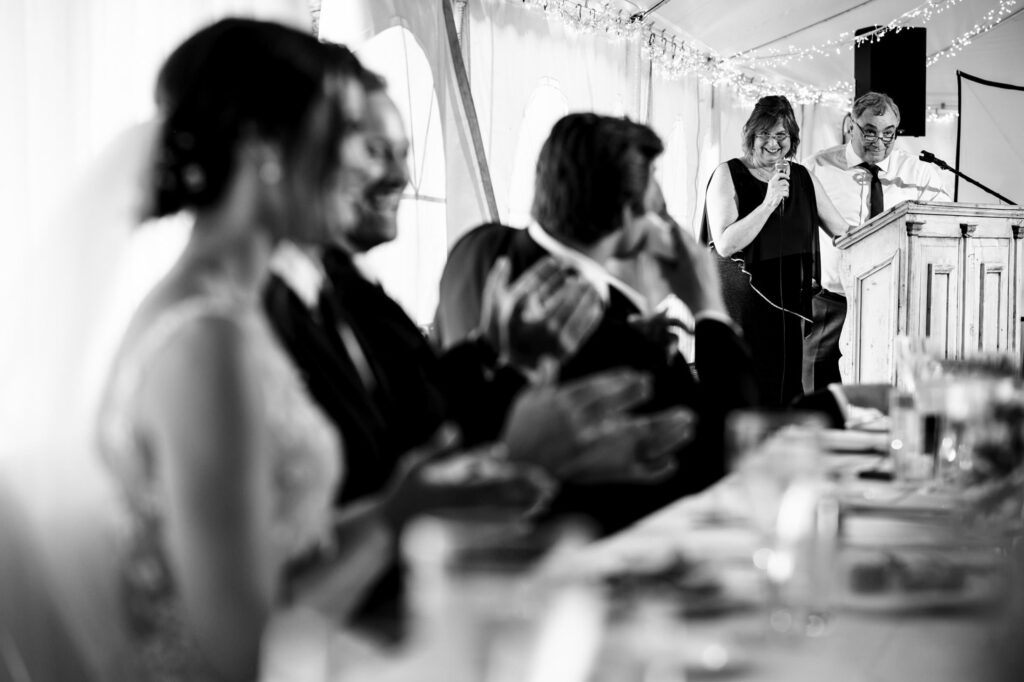 Guests applaud speakers at a wedding reception.