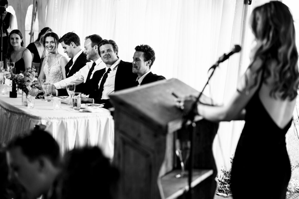 Woman speaking at a podium to a seated group at a formal event.
