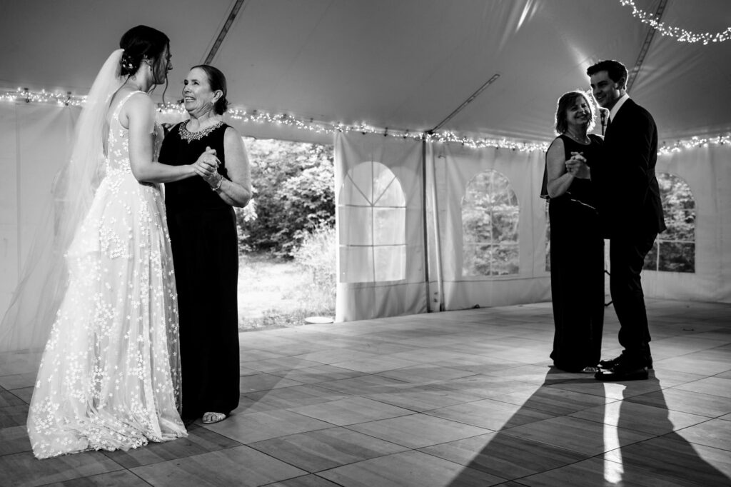 Two couples dance inside a tent at a wedding reception.