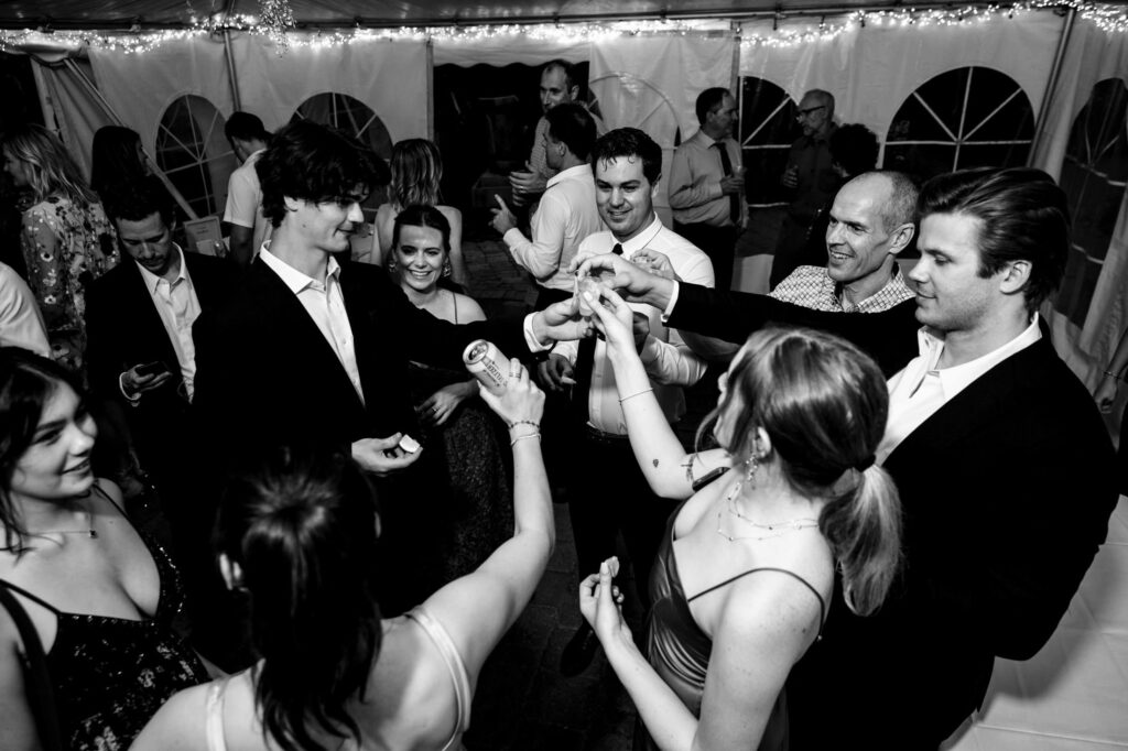 Group of people toasting with drinks at a lively indoor party.