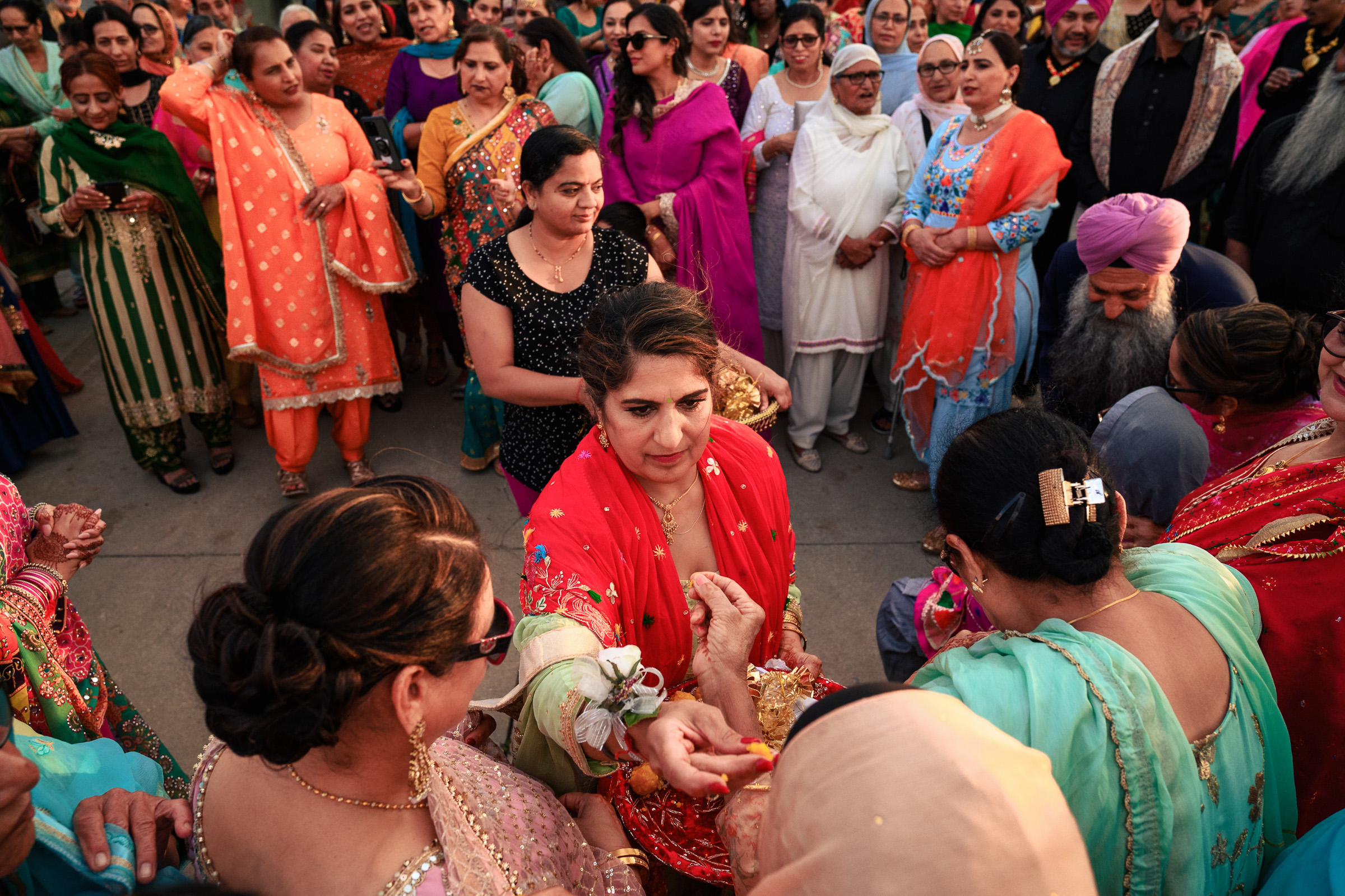 A group of people in colorful traditional attire gather for a celebration outdoors.