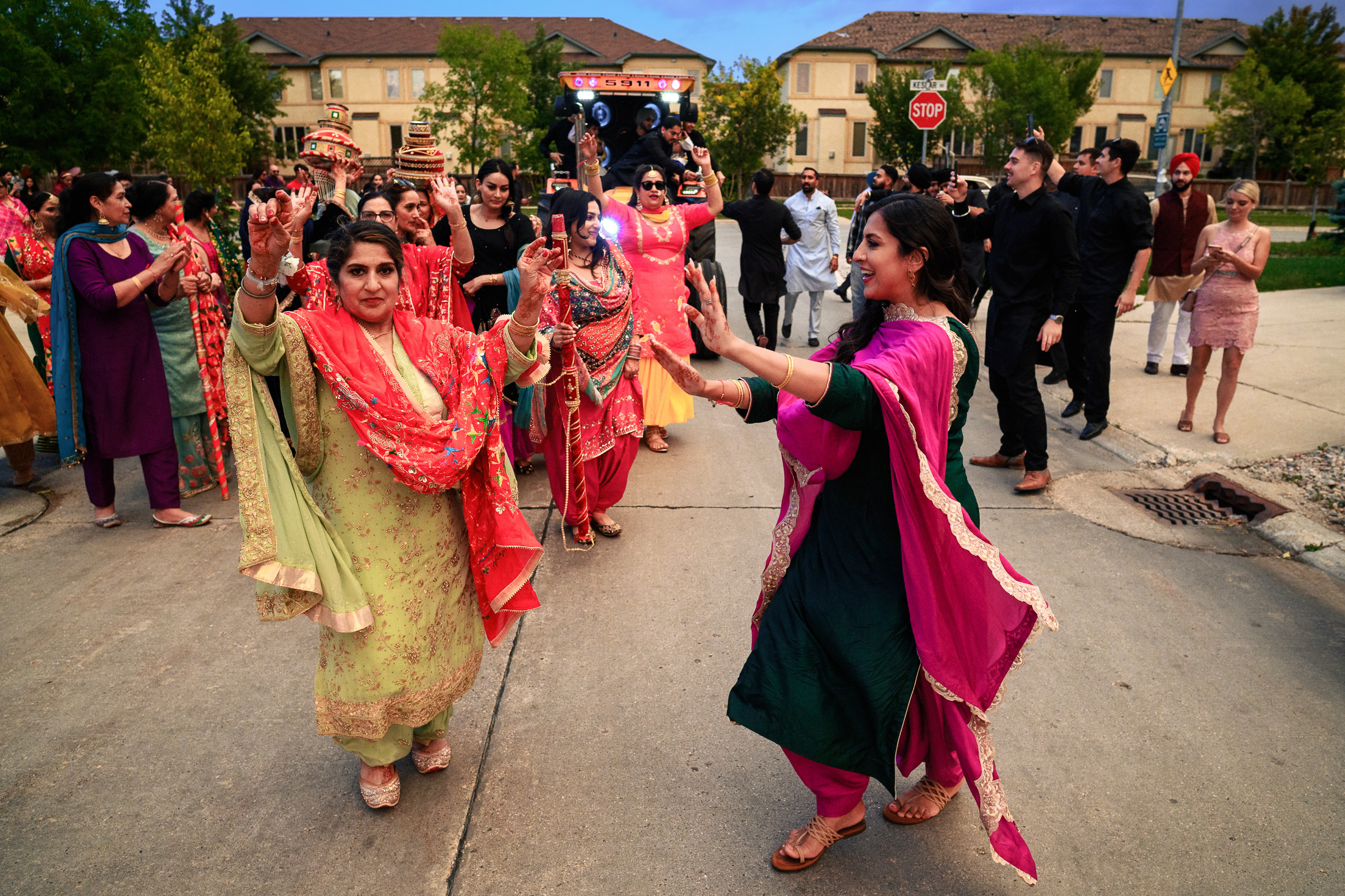 People in colorful traditional attire dancing on a street during a festive celebration.