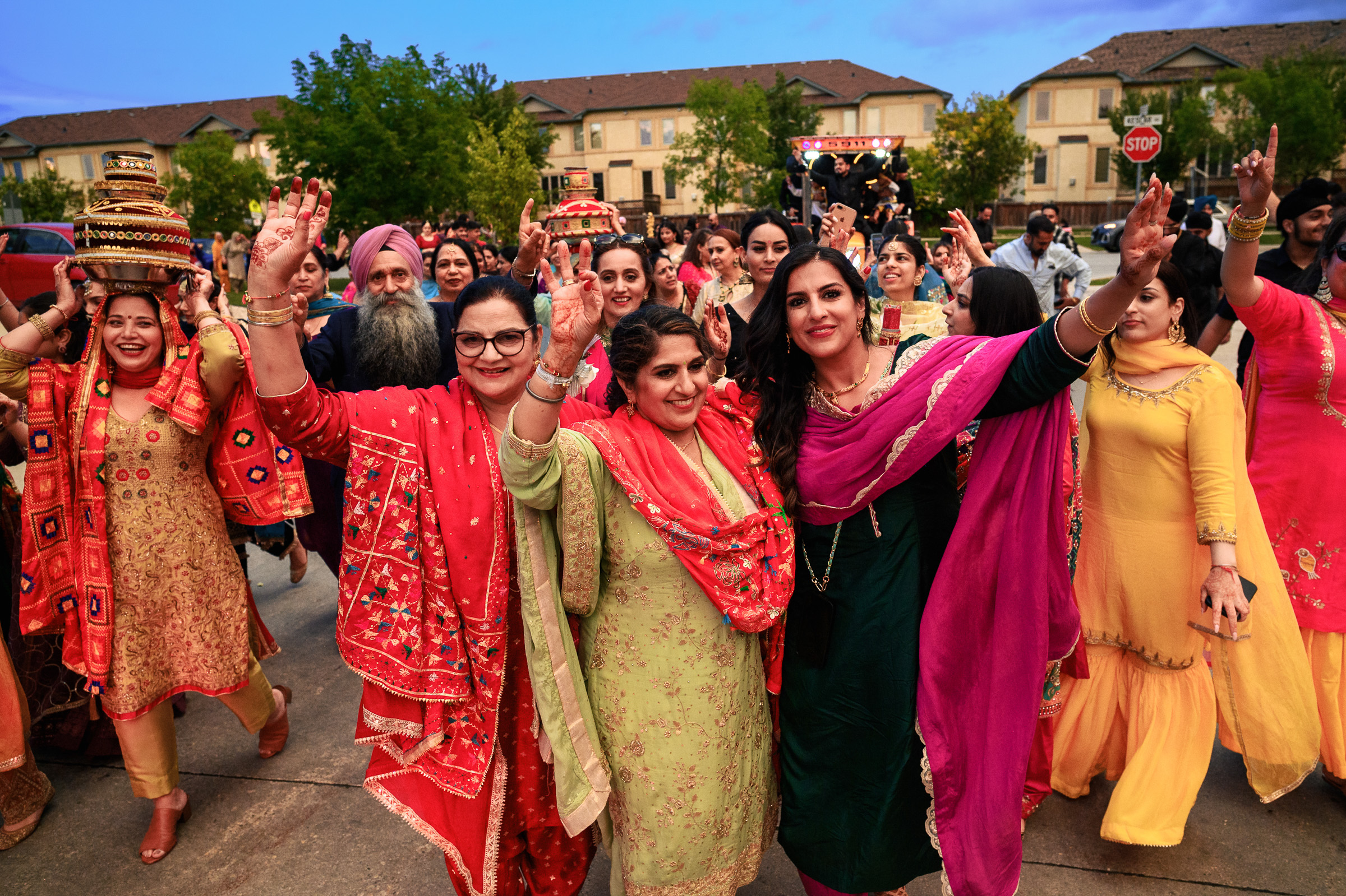 Group of people in colorful traditional attire walking and smiling outdoors.