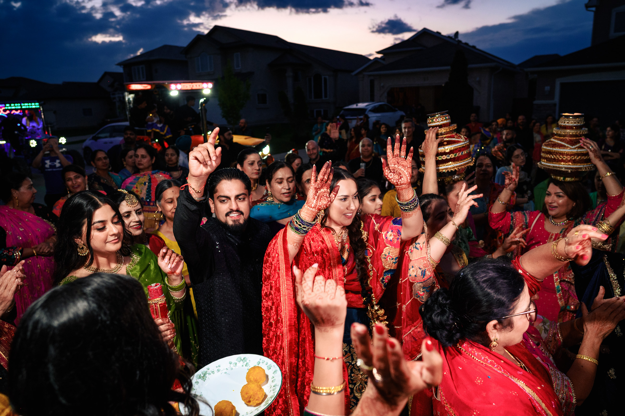 Group of people dancing in vibrant traditional attire at an outdoor celebration.
