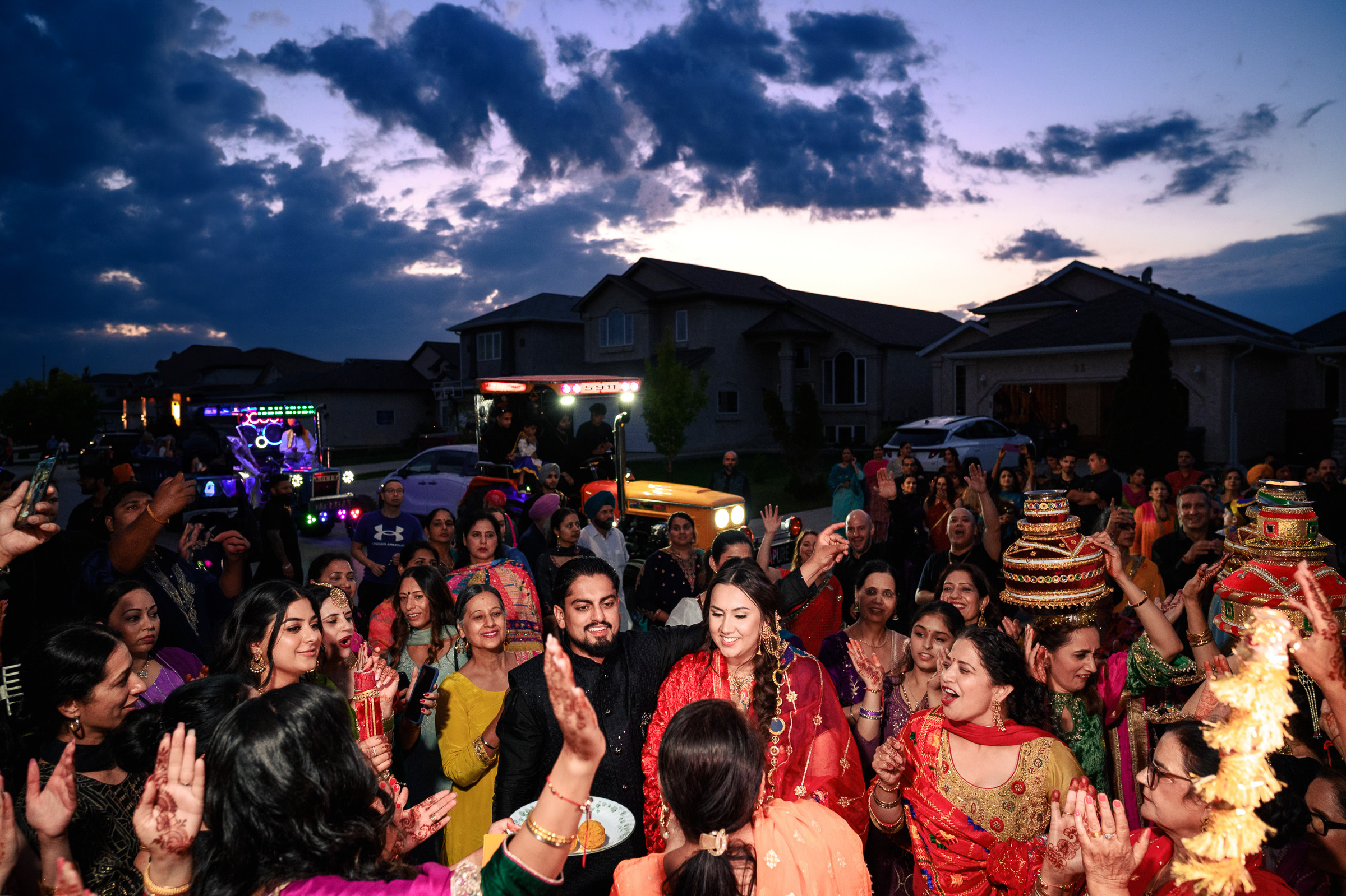 Group of people celebrating outdoors with colorful attire at dusk.