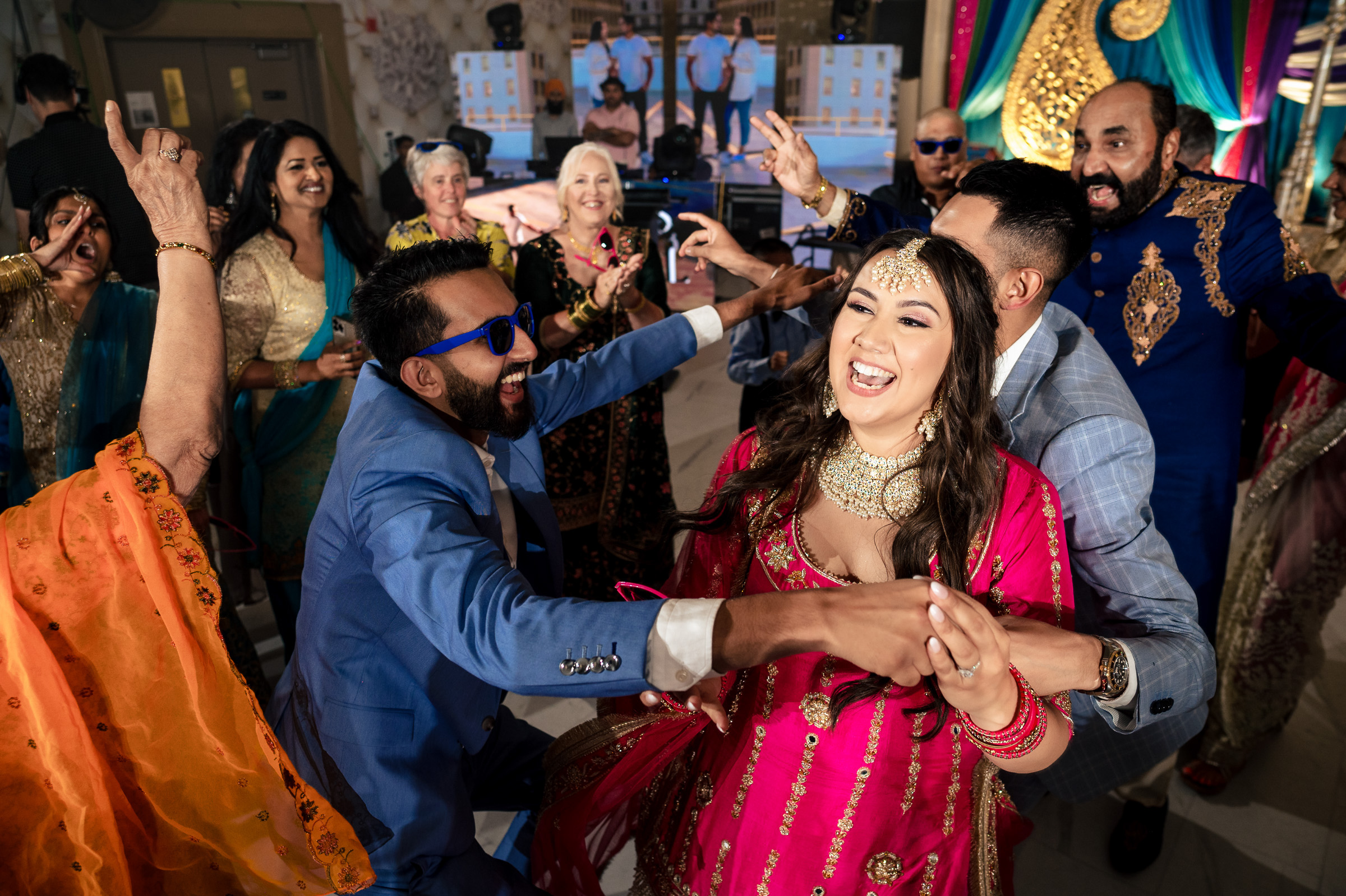 A joyful group dancing at a lively, colorful celebration indoors.