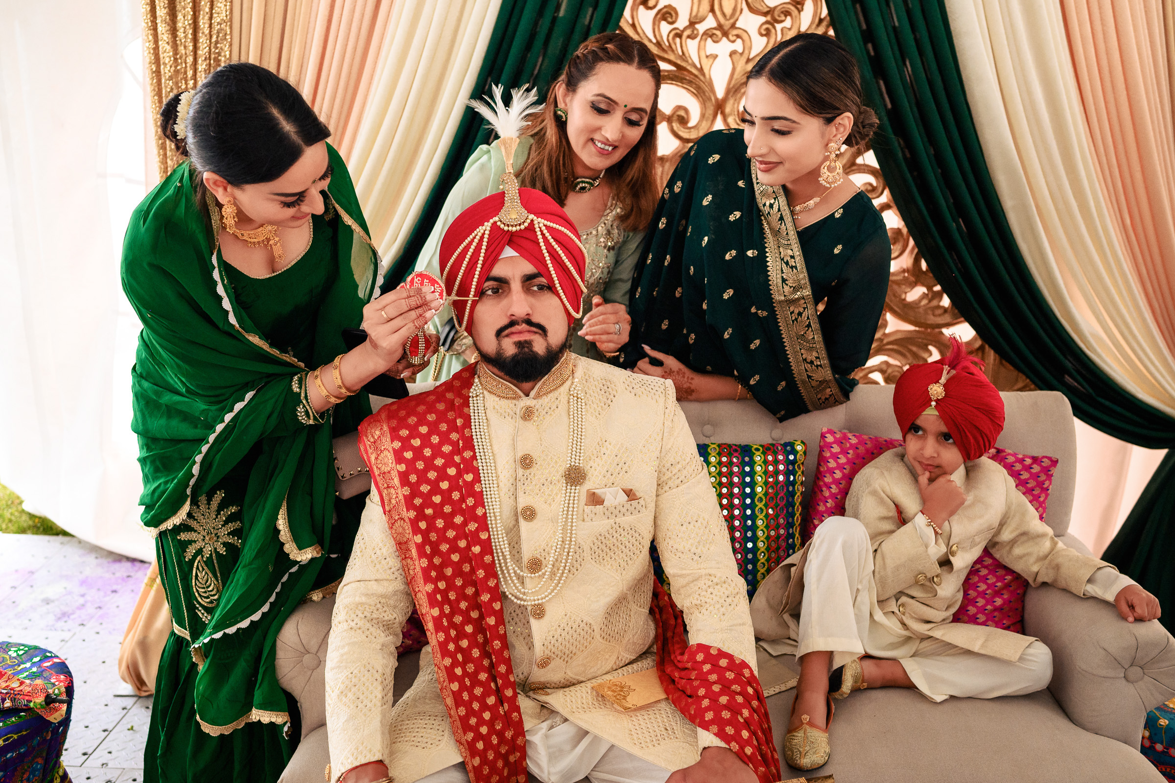 Man in traditional attire sitting, surrounded by women and a child in colorful clothing.