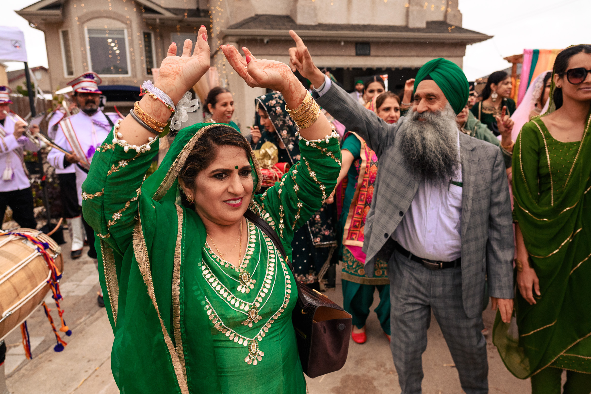 People in green traditional attire dancing at an outdoor celebration.