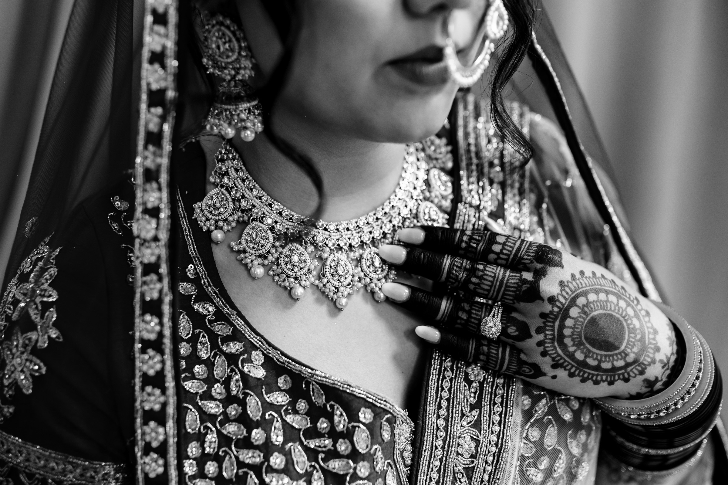 Person in intricate traditional attire and jewelry with detailed henna on hand.