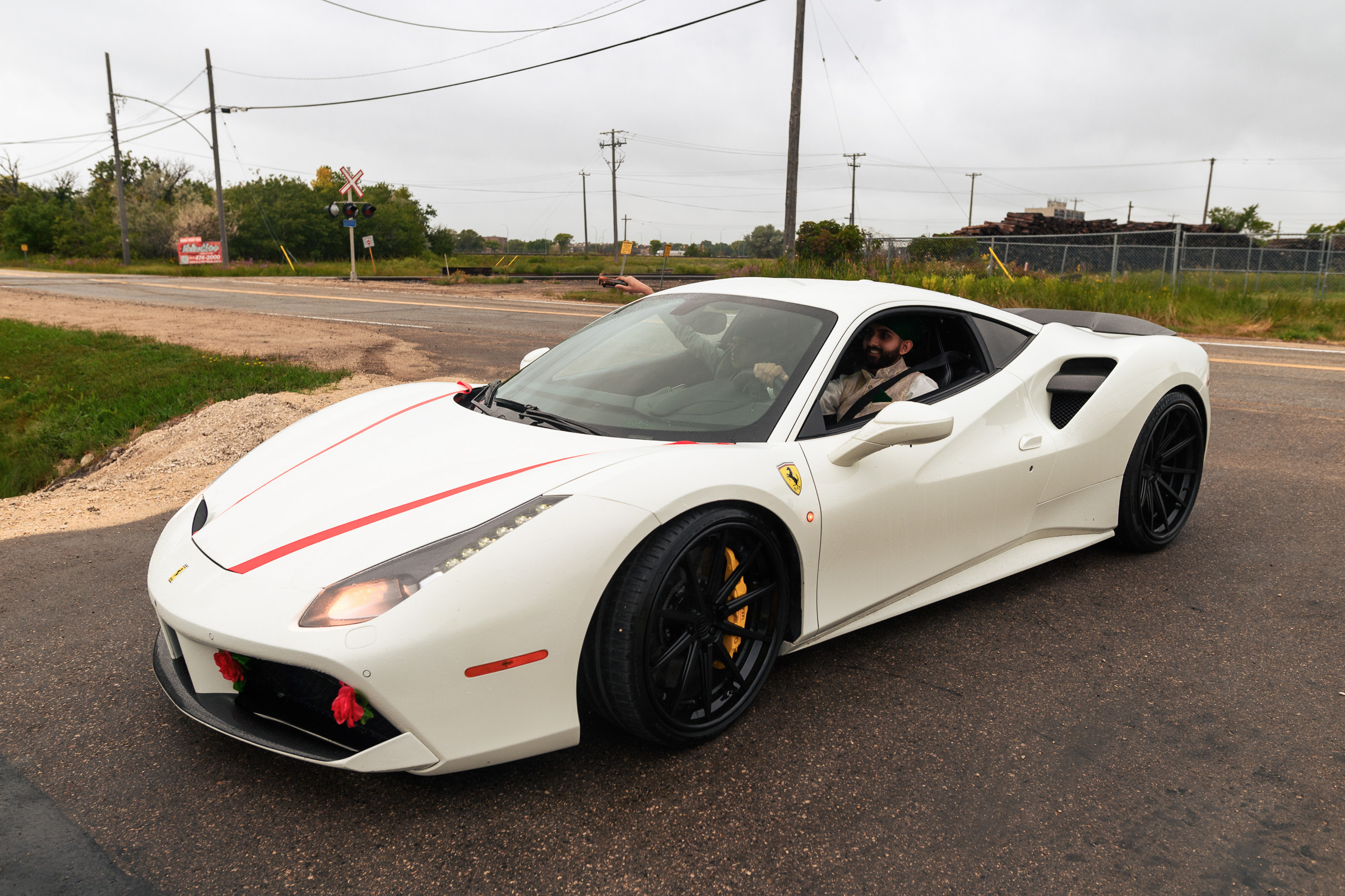 White convertible sports car on a rural road with a driver and a passenger.