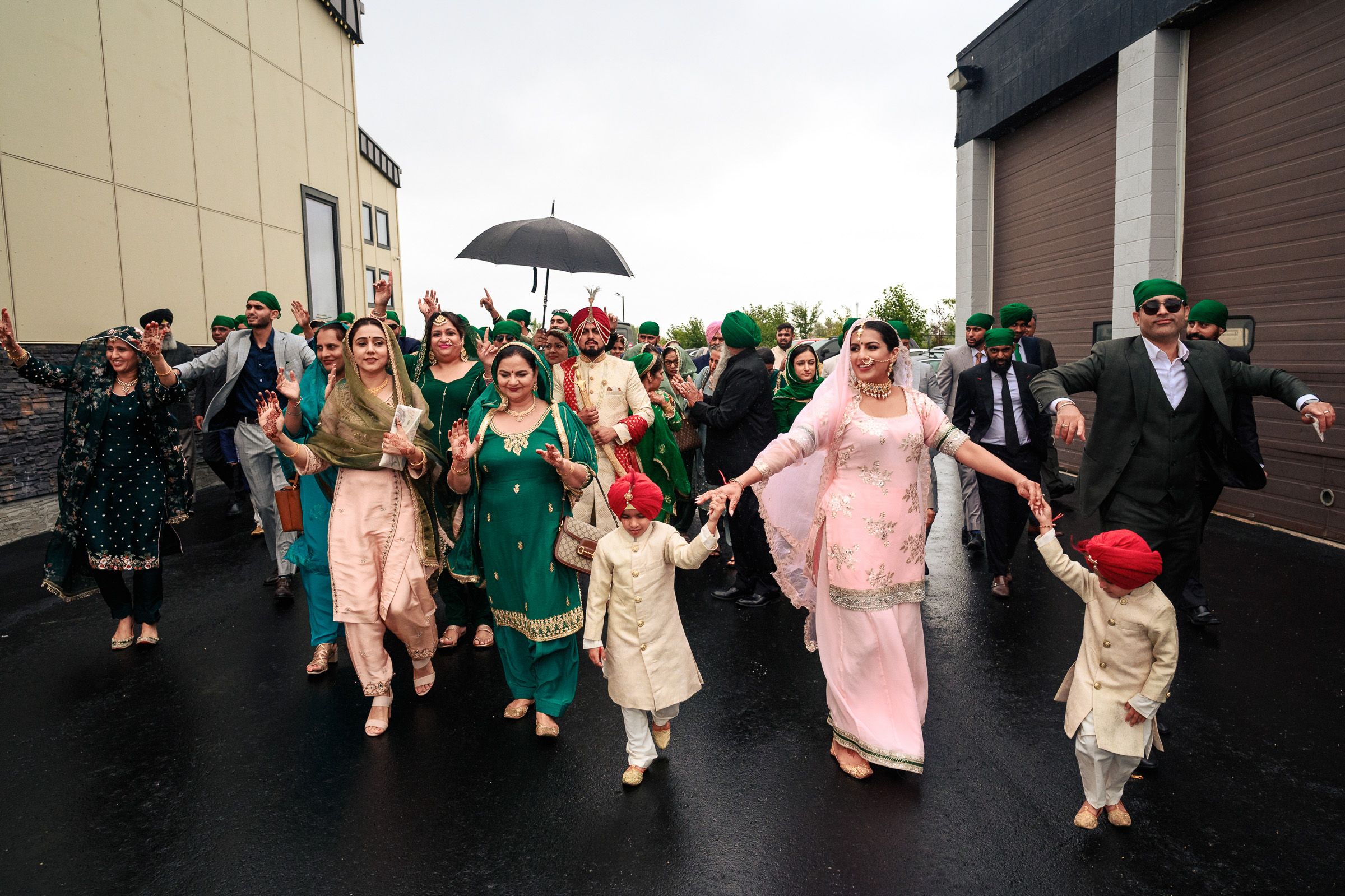Group of people in traditional attire celebrating outside on a rainy day.