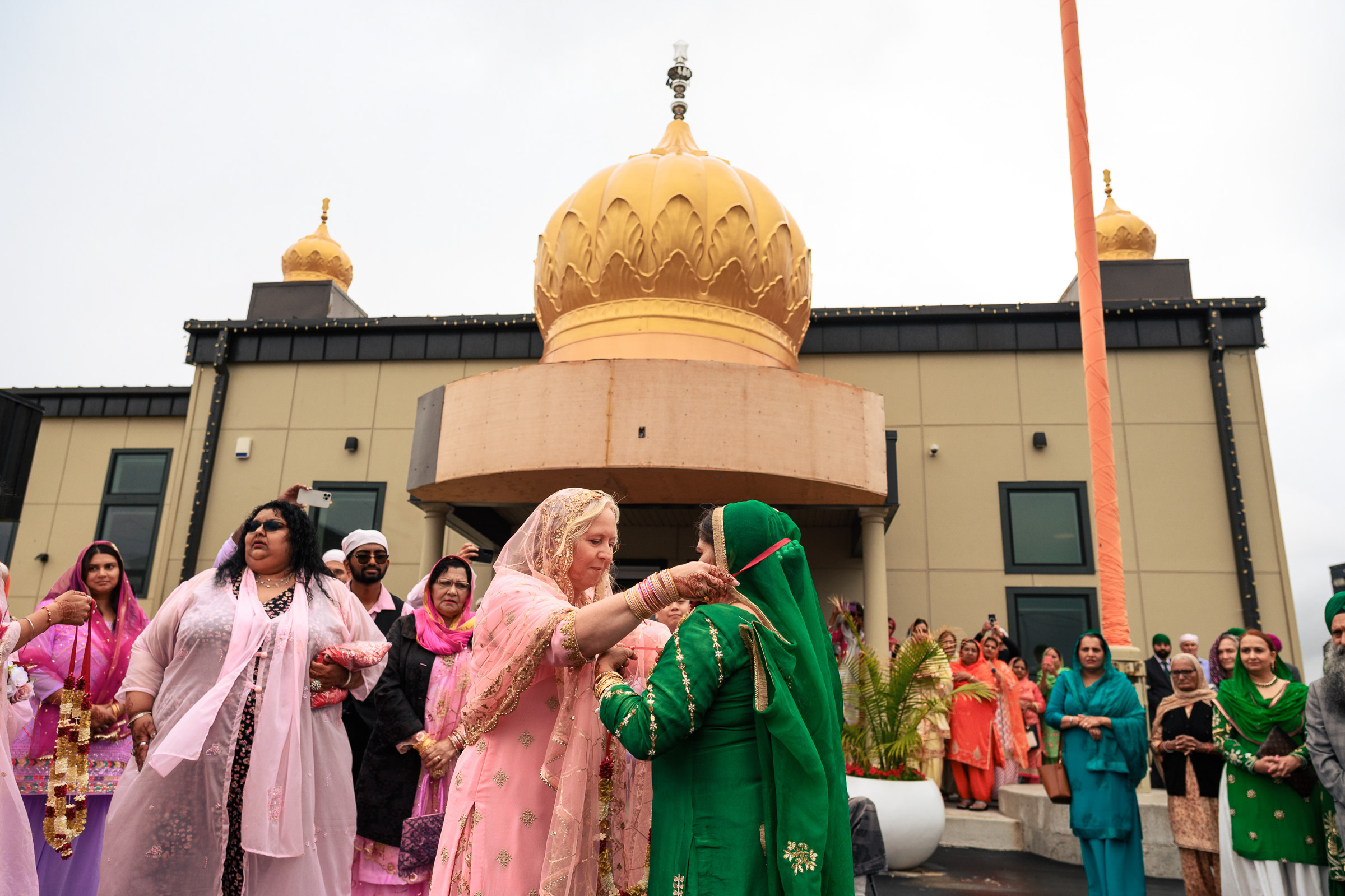 A group of people in colorful attire outside a building with golden domes.