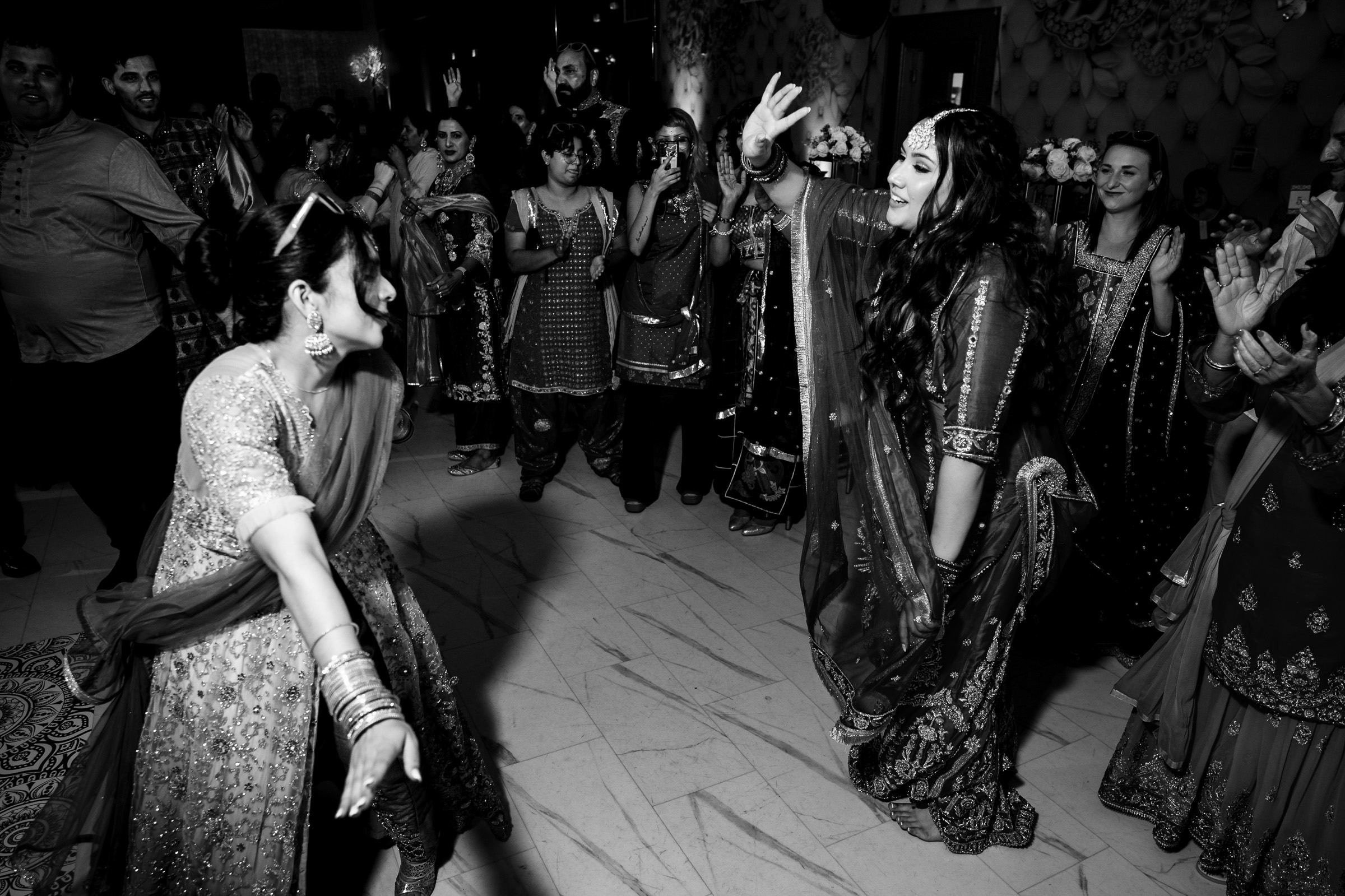 Two women in traditional attire dancing at a festive gathering.