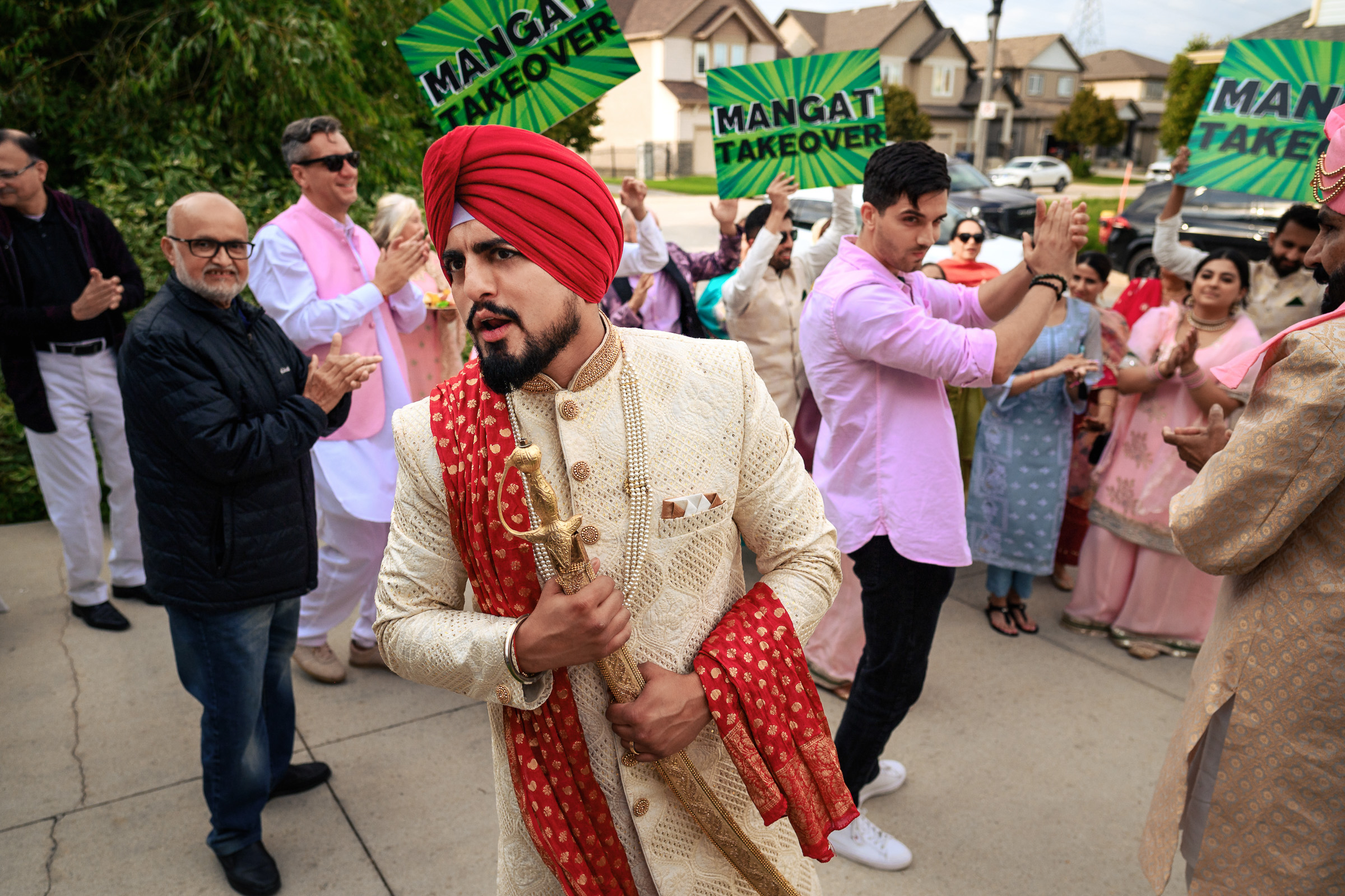 Man in traditional attire with a sword, surrounded by people holding "Mangat Takeover" signs.