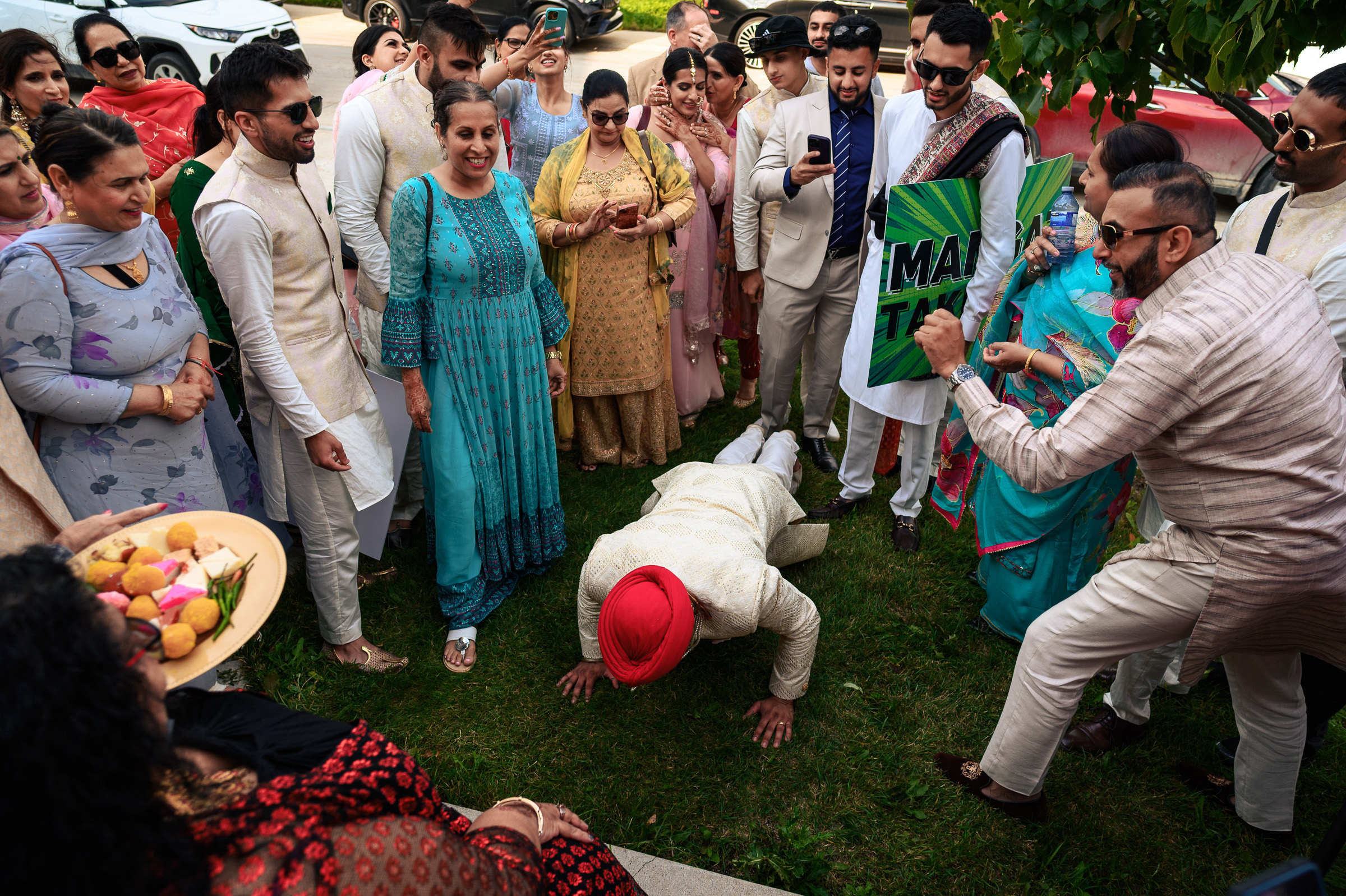 Person in traditional attire doing push-ups, surrounded by cheering people outdoors.