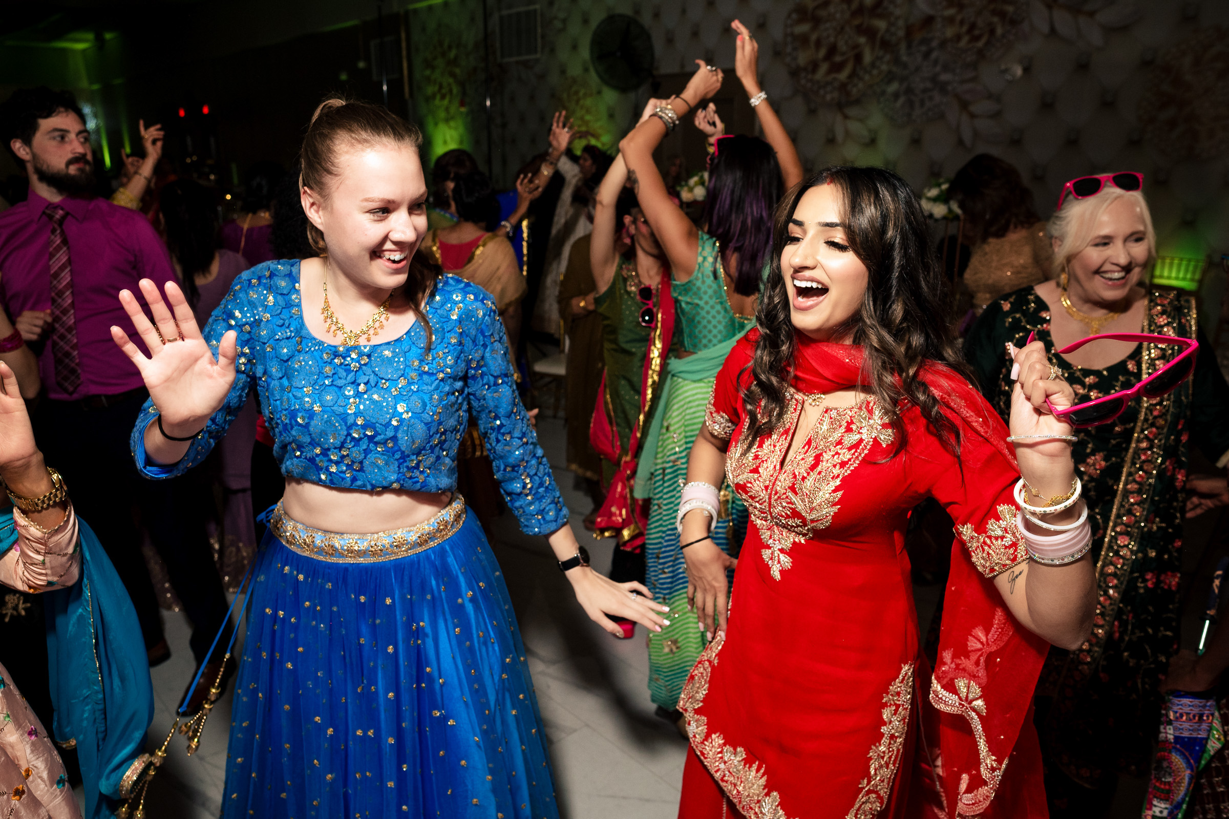 People dancing energetically at a festive event, wearing colorful traditional attire.