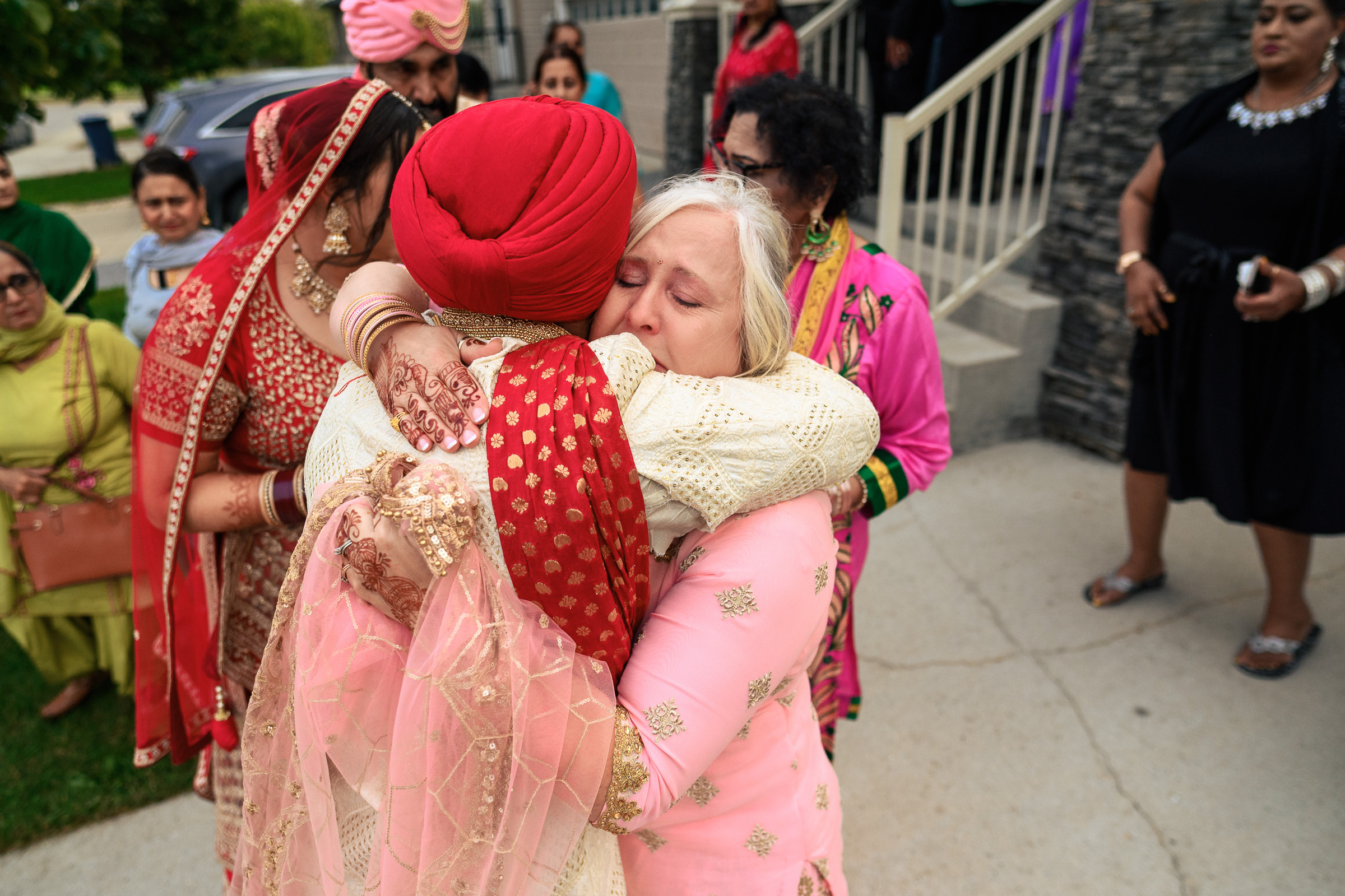 Two women in colorful attire embrace at an outdoor gathering.