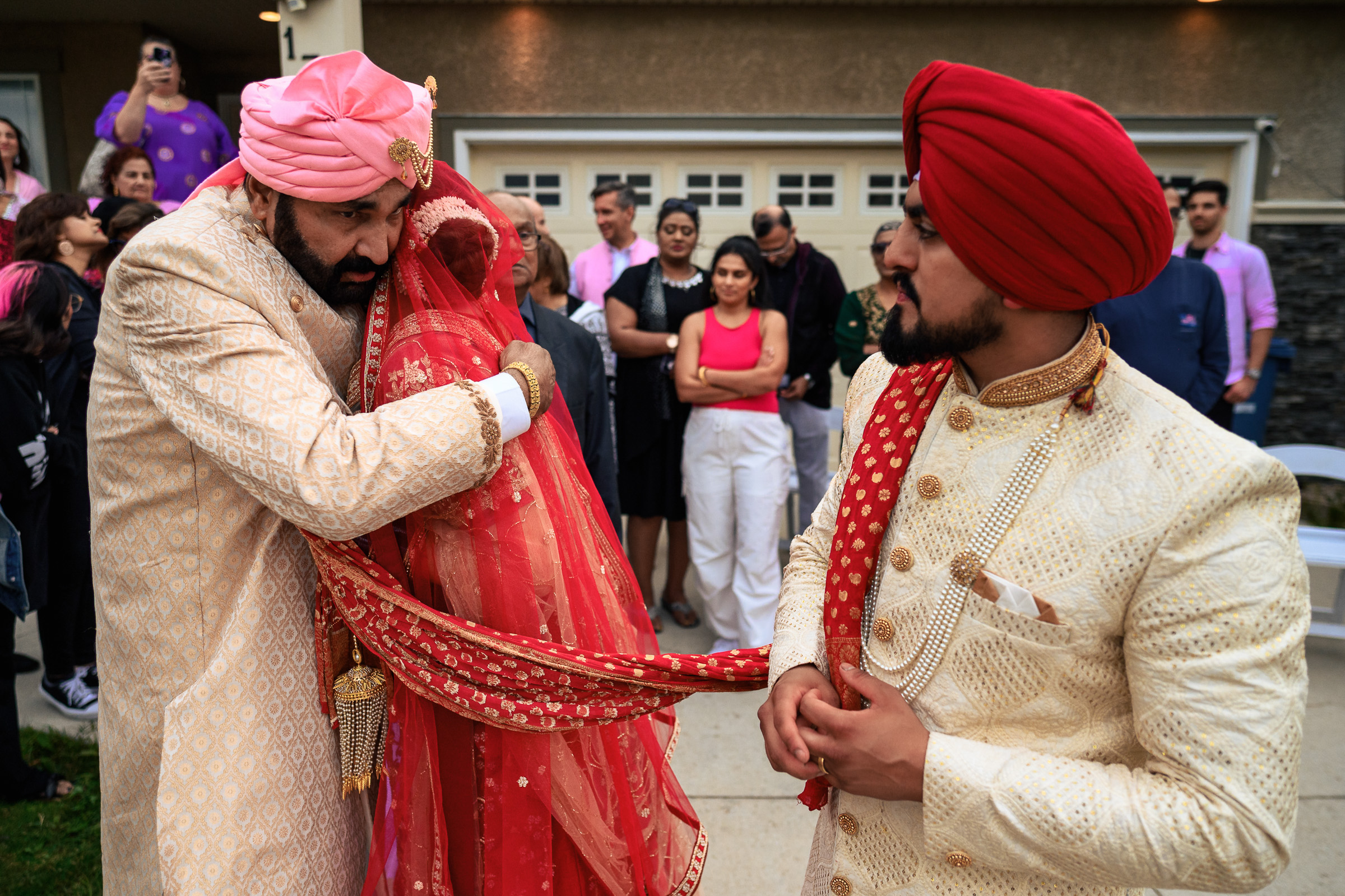 A bride and groom in traditional attire during a wedding ceremony with guests in the background.