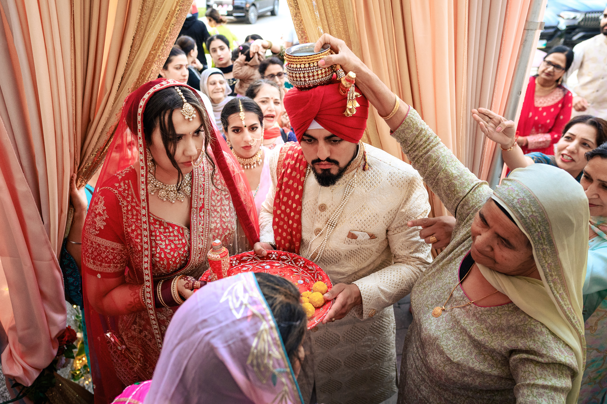 Traditional Indian wedding entrance with bride and groom in ceremonial attire under a canopy.