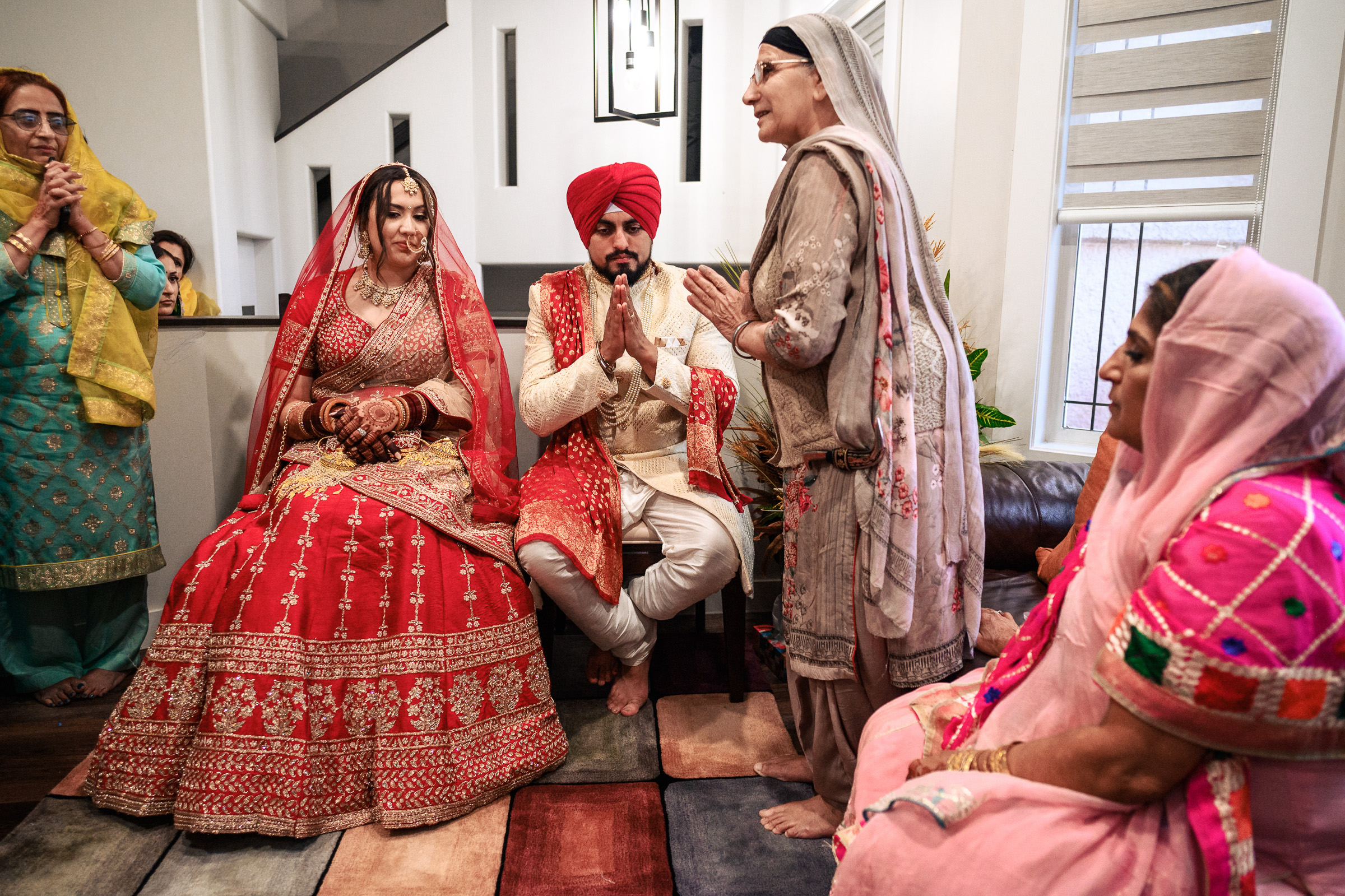 A couple in traditional attire participate in a cultural ceremony indoors.
