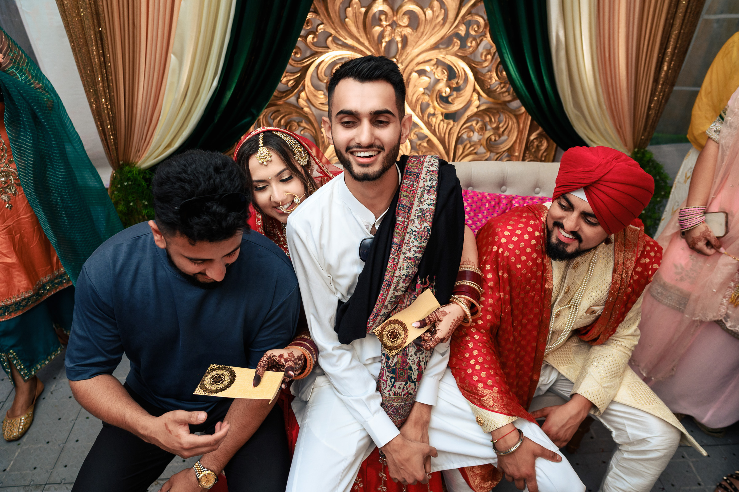 Four people in traditional attire enjoying a festive celebration with decorative background.