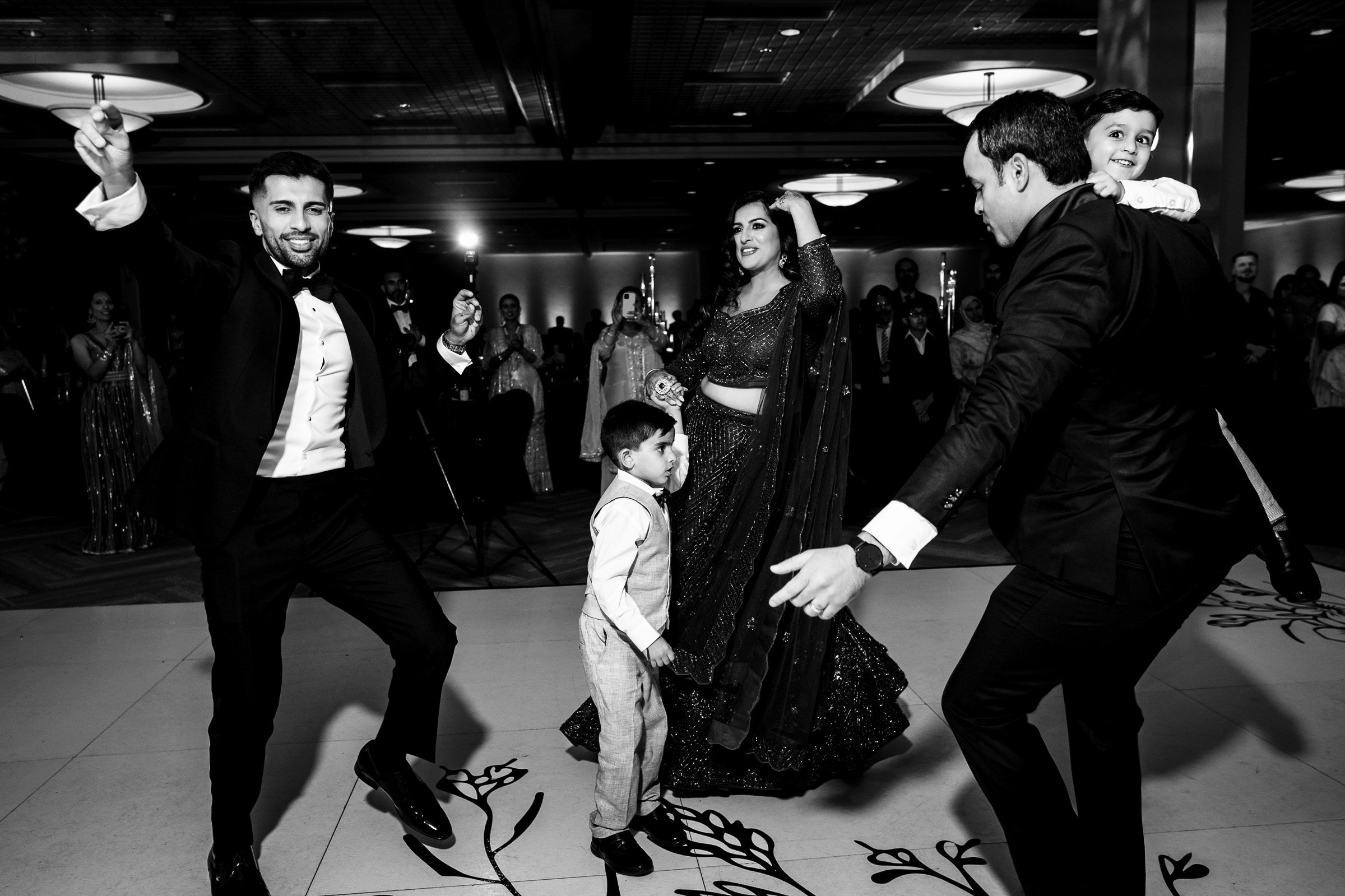 People dancing and celebrating at a formal indoor event, with adults and children.