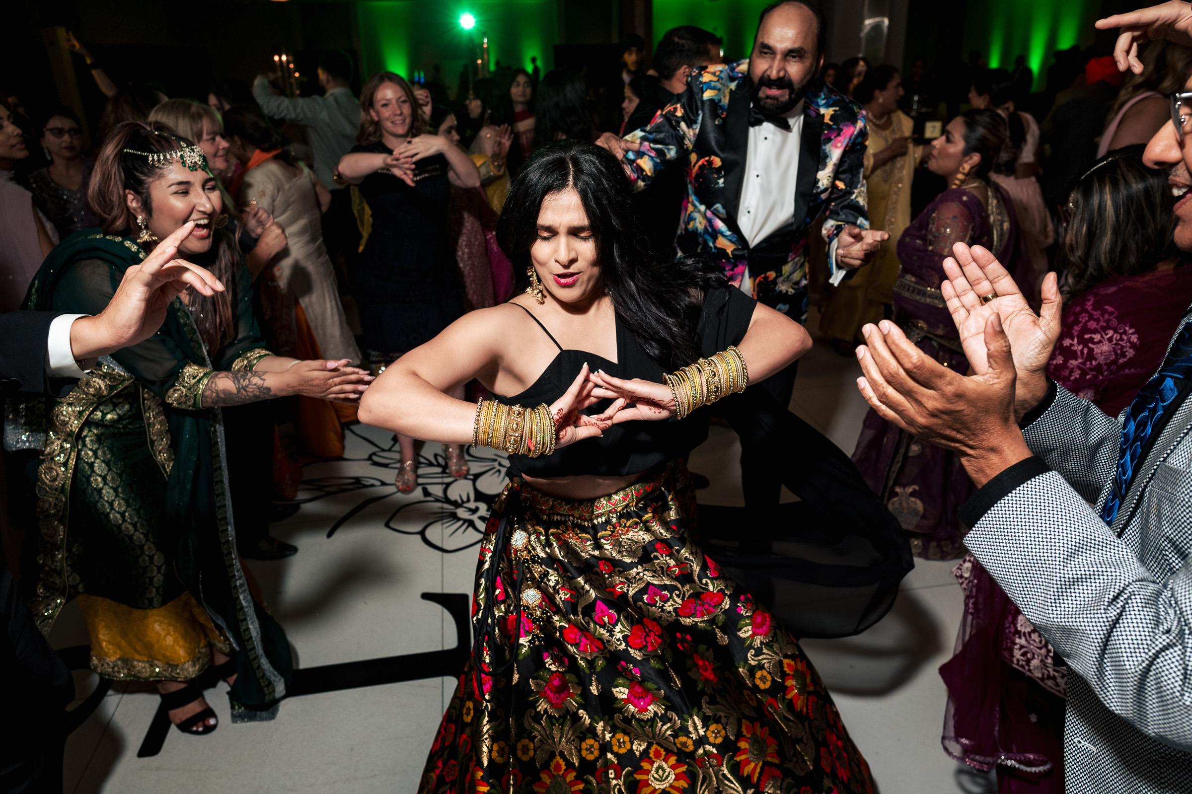 People dancing energetically at a festive indoor event with colorful outfits and joyful expressions.