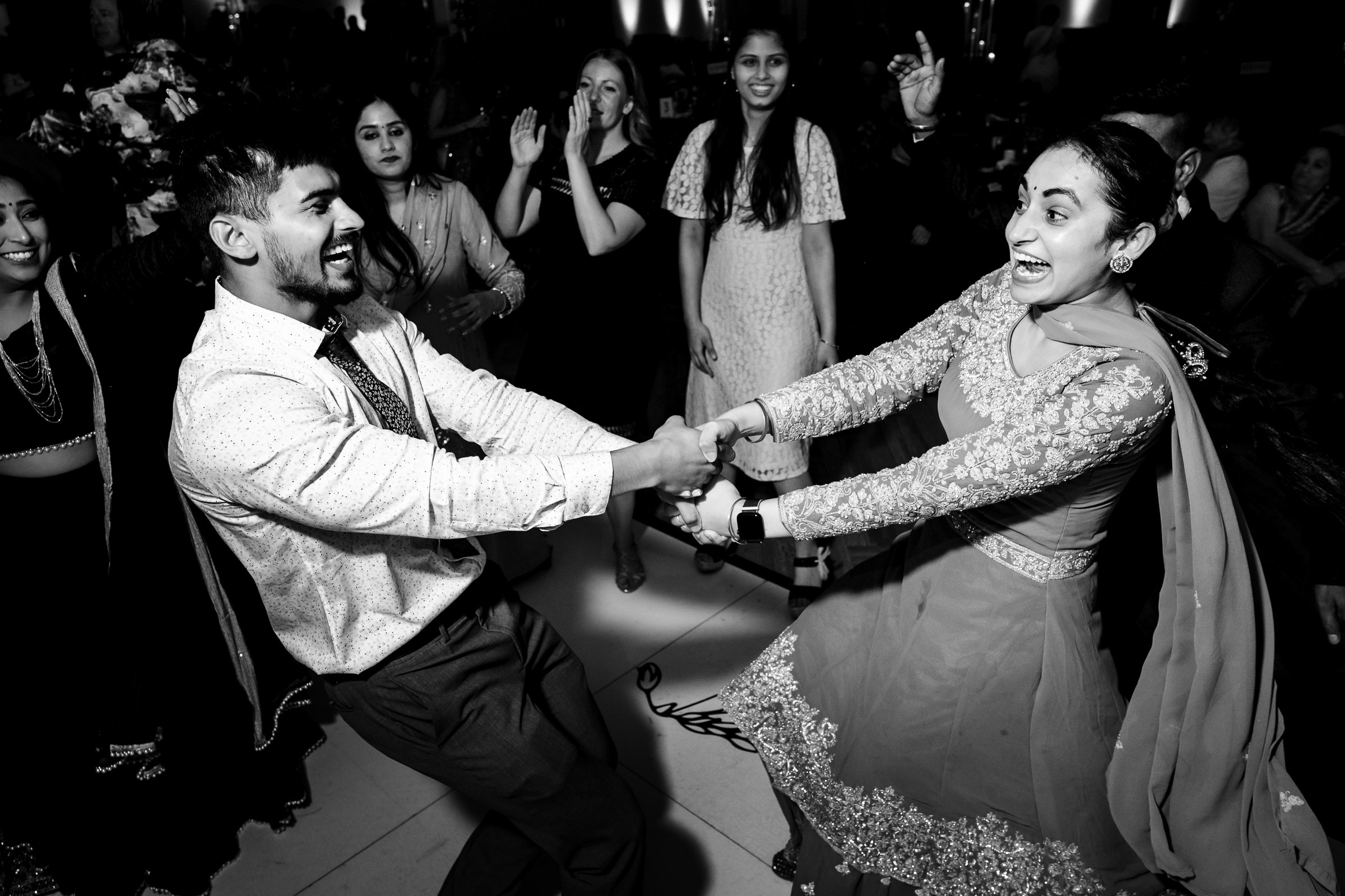 Two people in traditional attire joyfully dancing at an event.