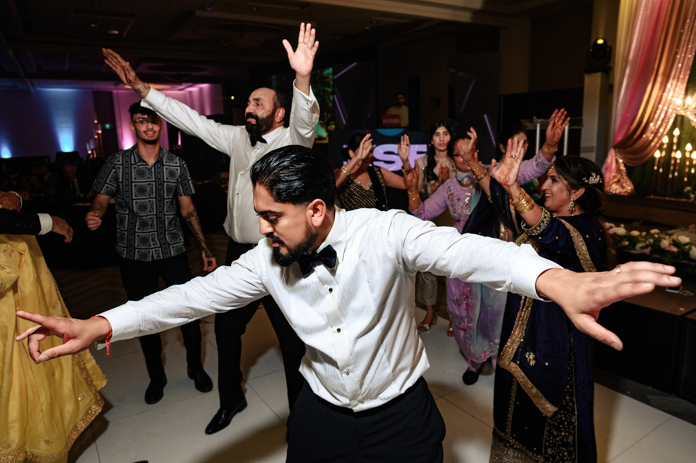 A group of people dancing energetically at a festive indoor event.