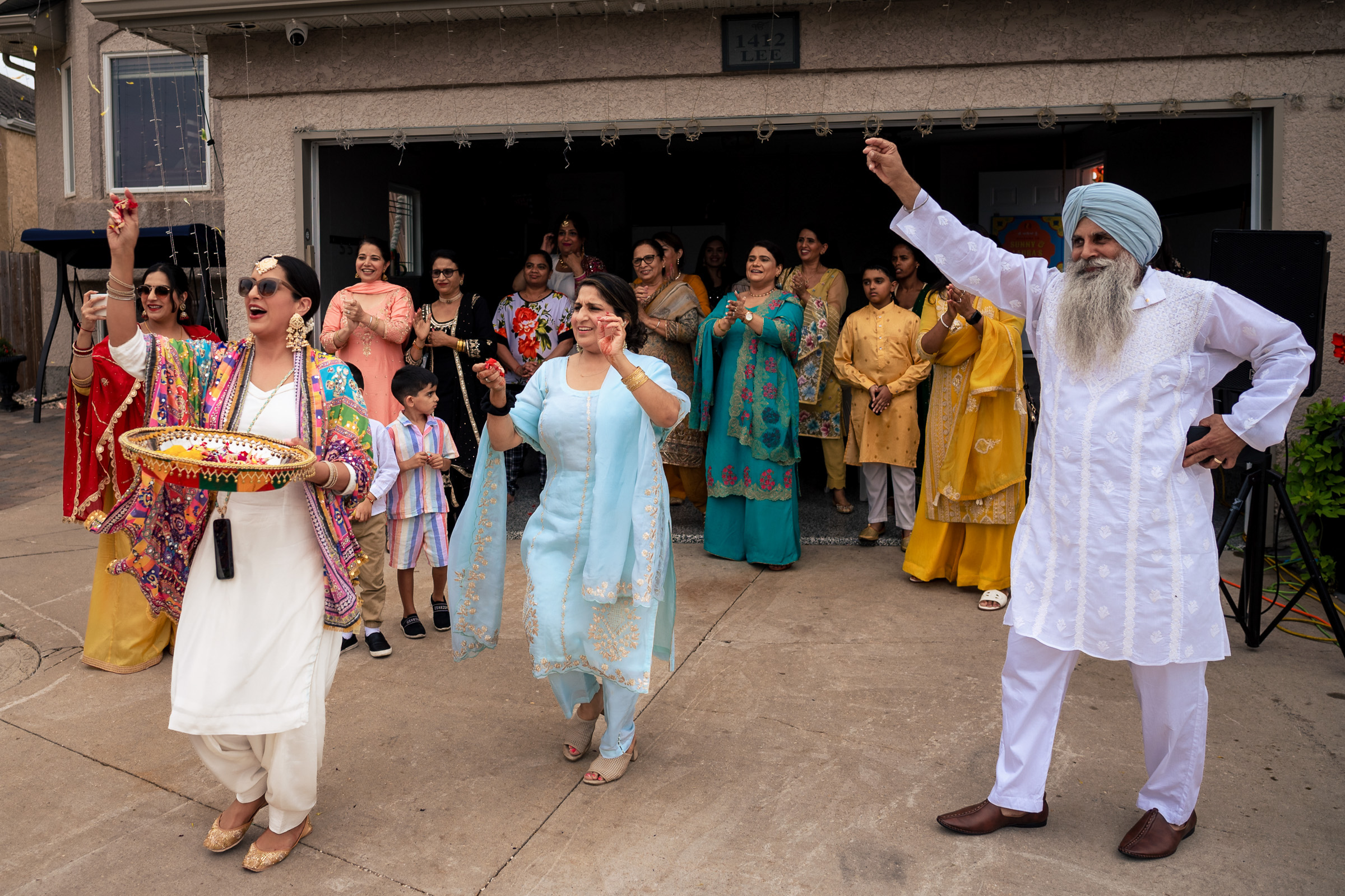 A group of people dancing outdoors, some wearing traditional clothing.