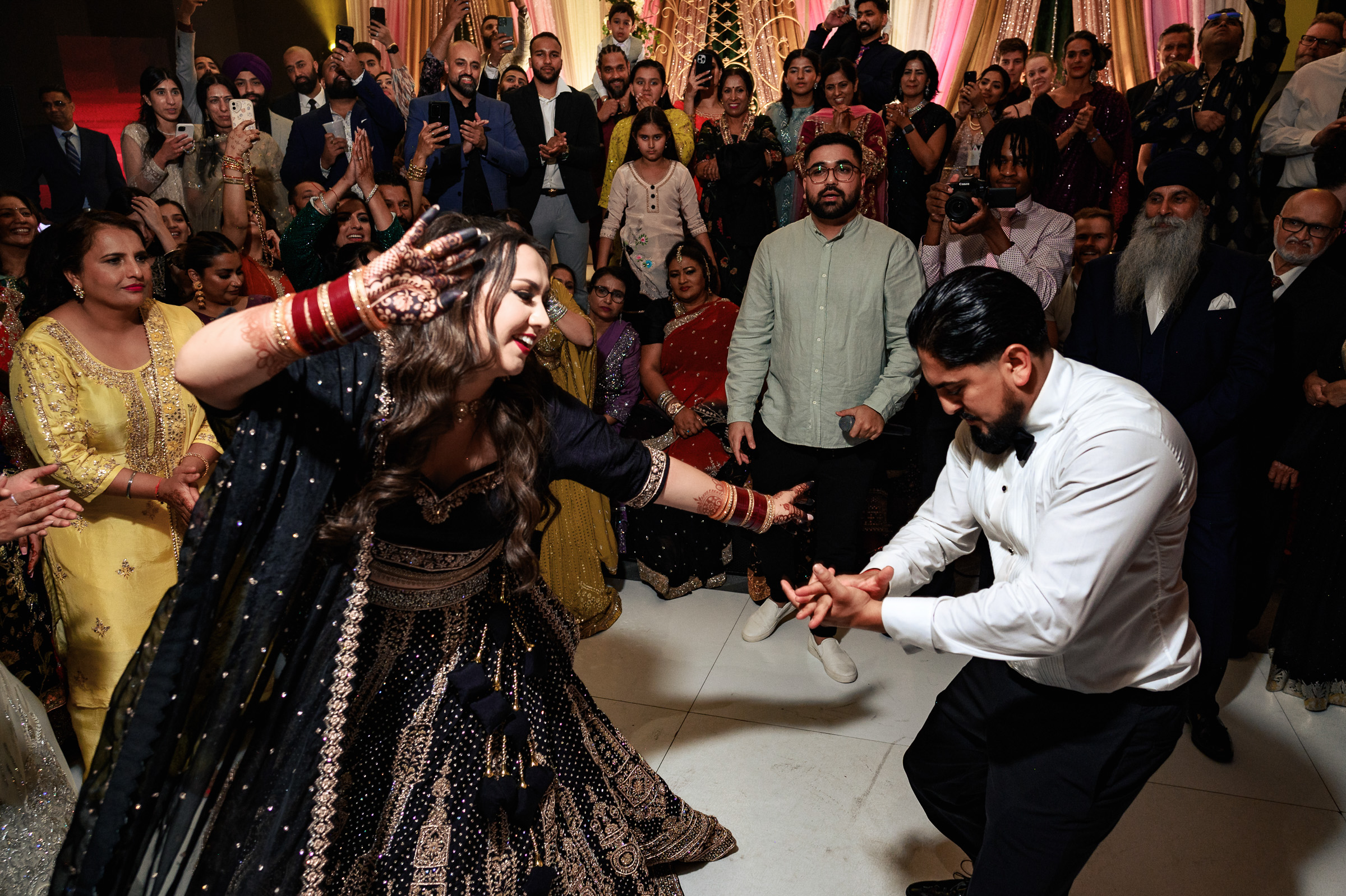 A couple dances energetically surrounded by a cheering crowd at a celebration.