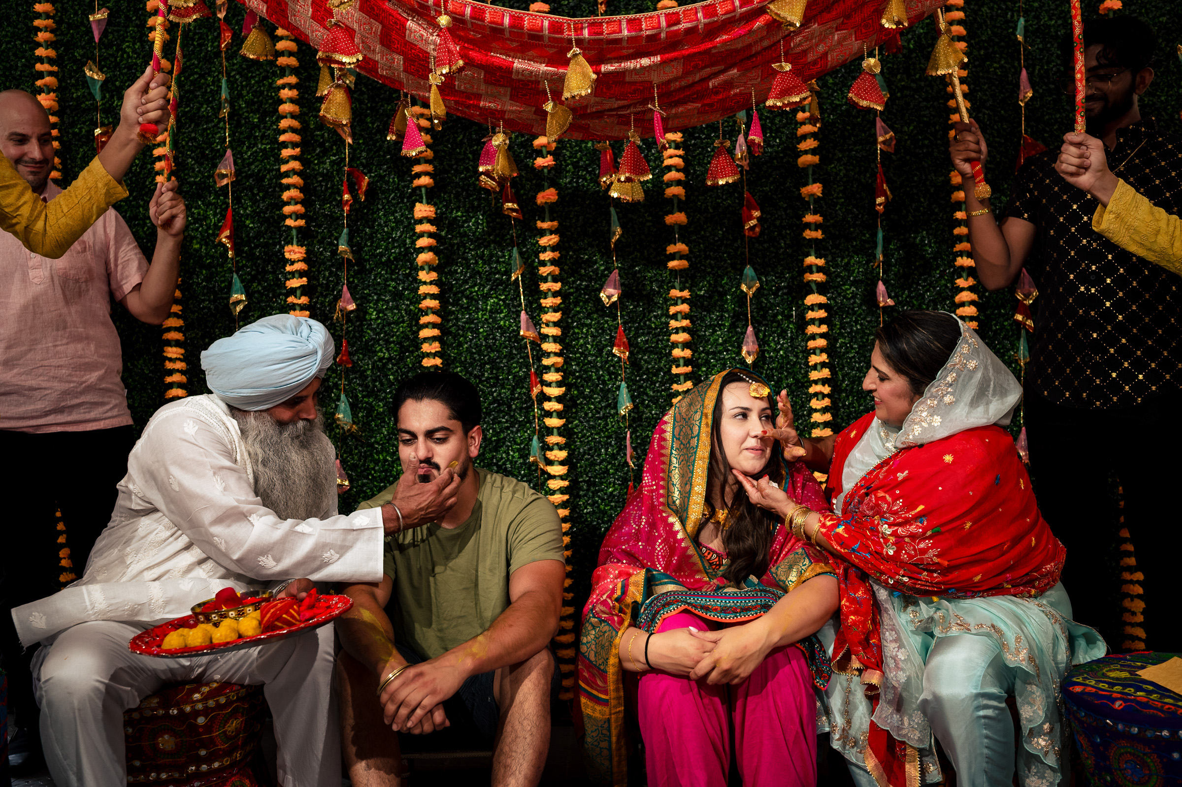 A traditional ceremony with participants in colorful attire and floral decorations.