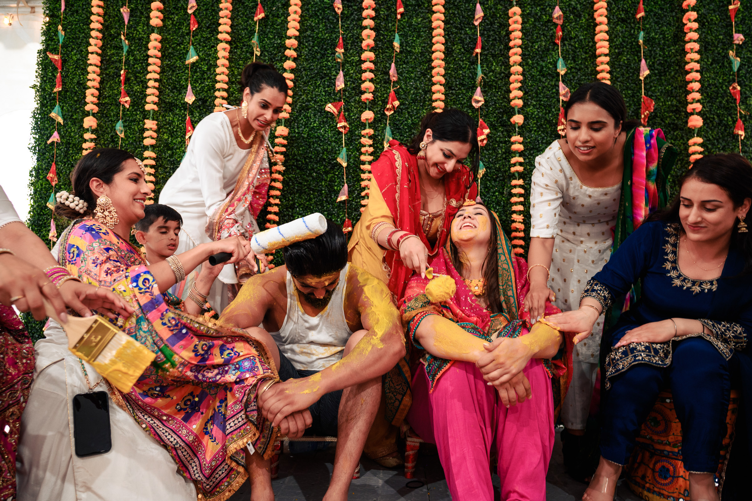 A group celebrating a traditional ceremony with turmeric and colorful attire.