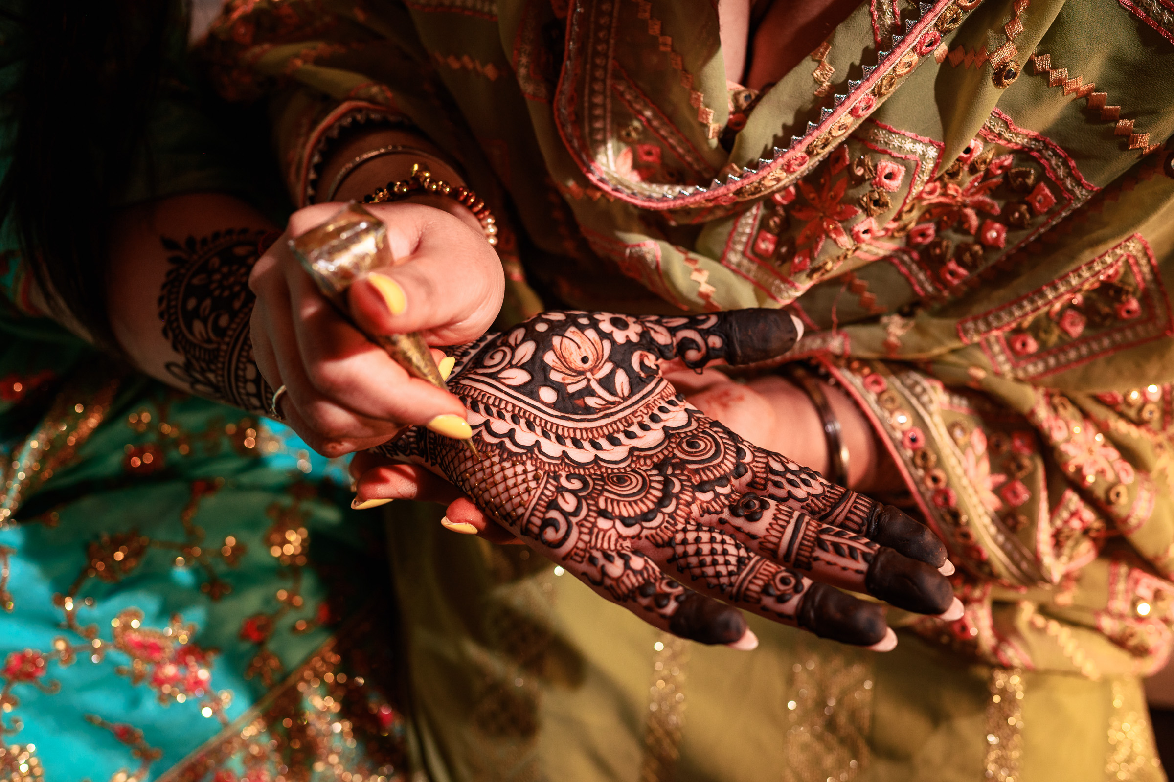Close-up of intricate henna design being applied to a person's palm at an event.