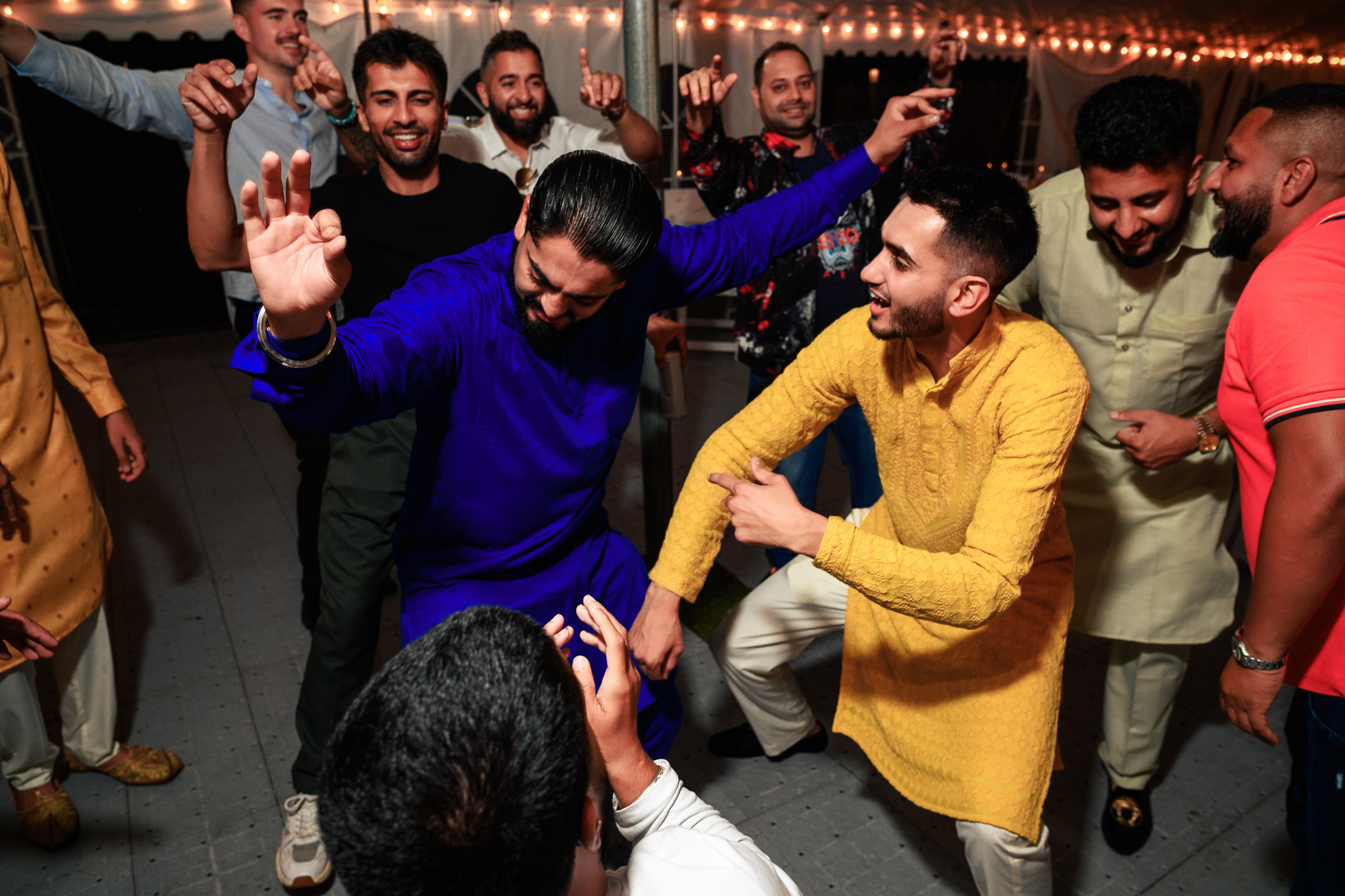 A group of men in traditional attire dance at a festive gathering.