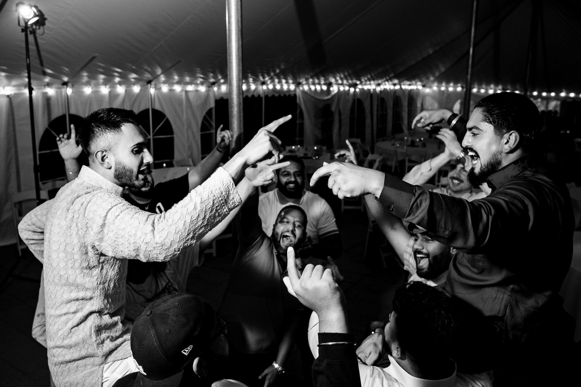 People joyfully dancing and cheering in a tented venue.