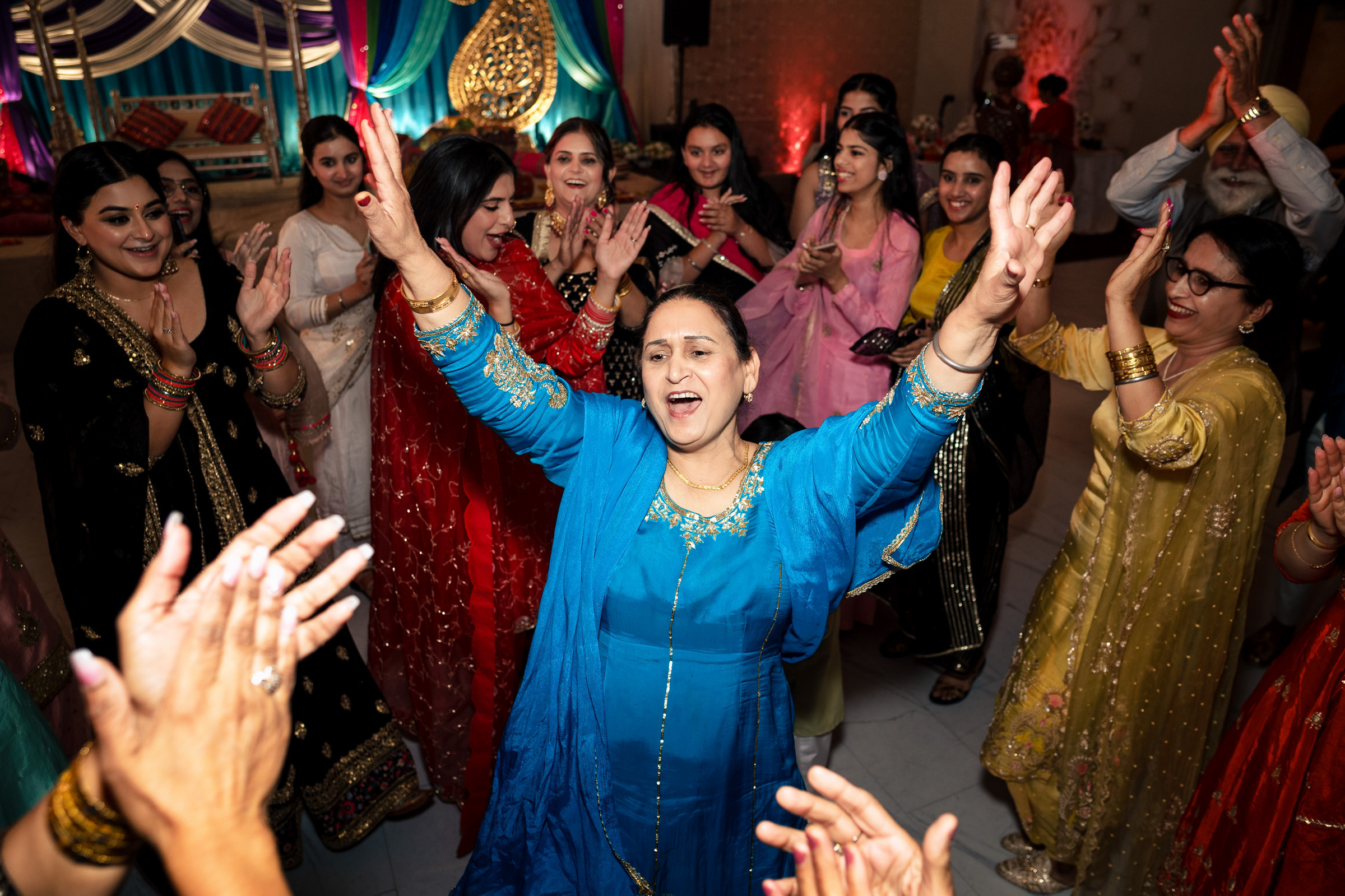Group of people joyfully dancing at a celebratory event in colorful traditional attire.