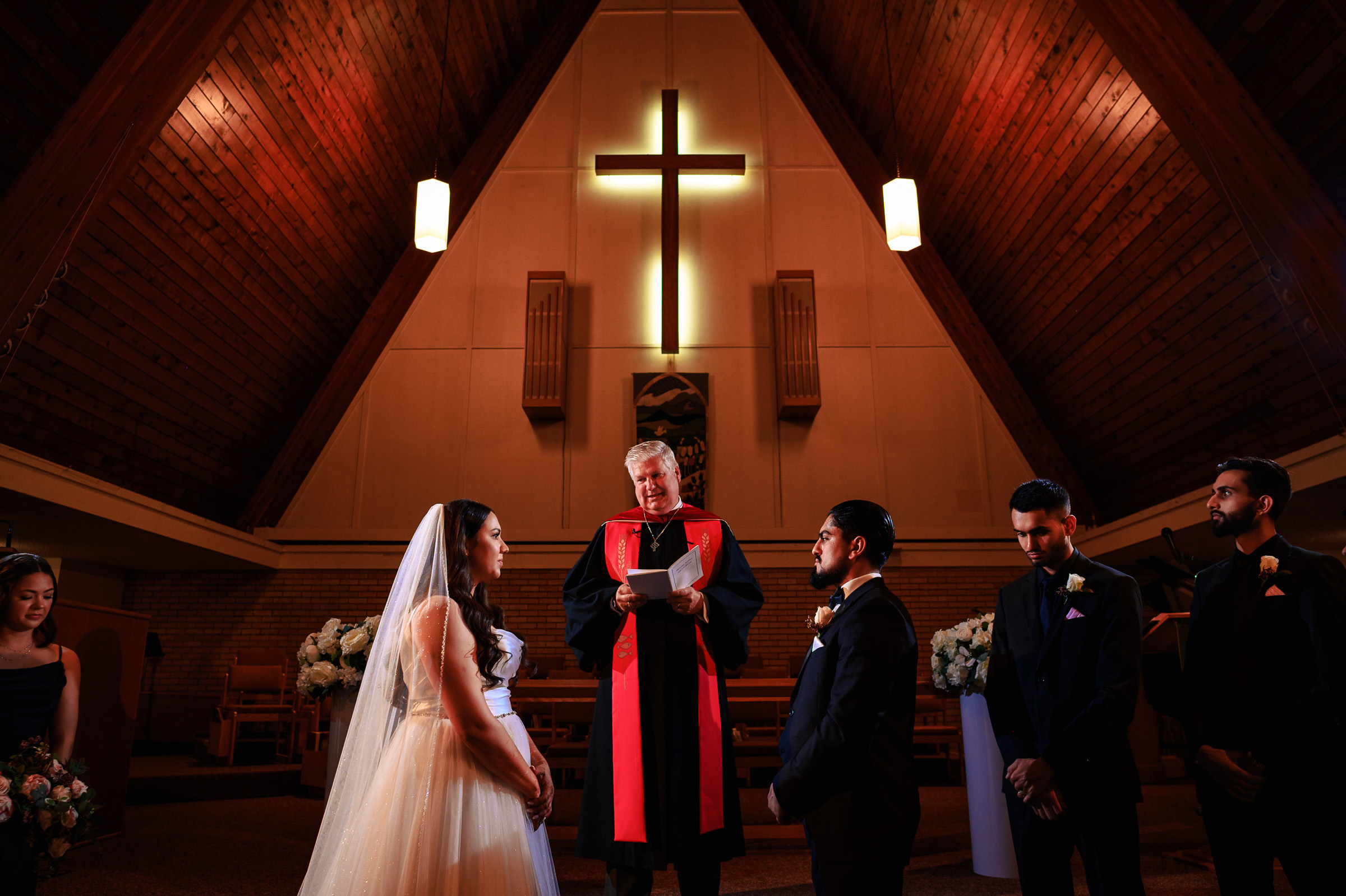 Wedding ceremony in a church with bride, groom, officiant, and two groomsmen.