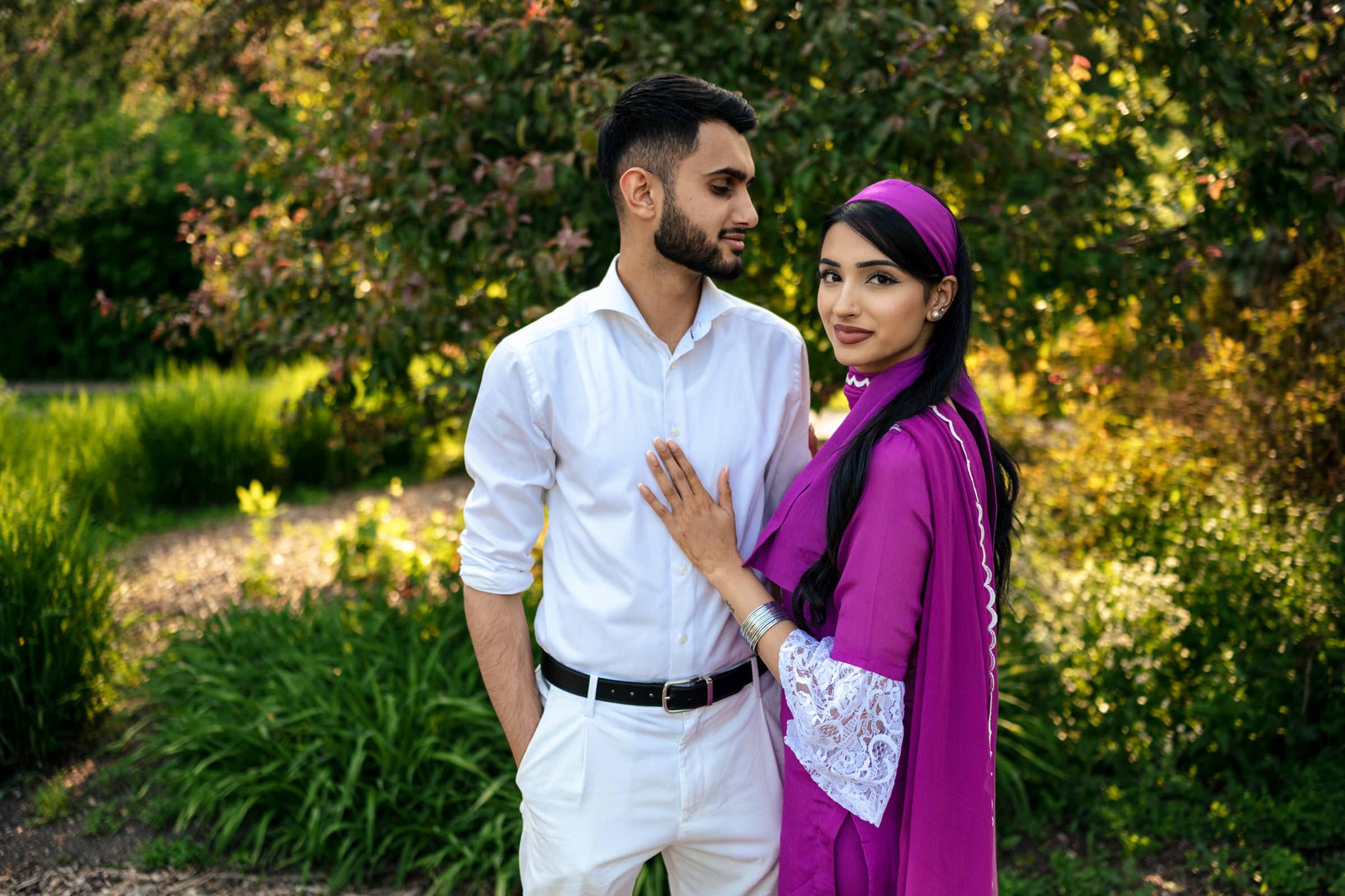 A couple celebrates engagement at home, the woman in a purple outfit in the garden.