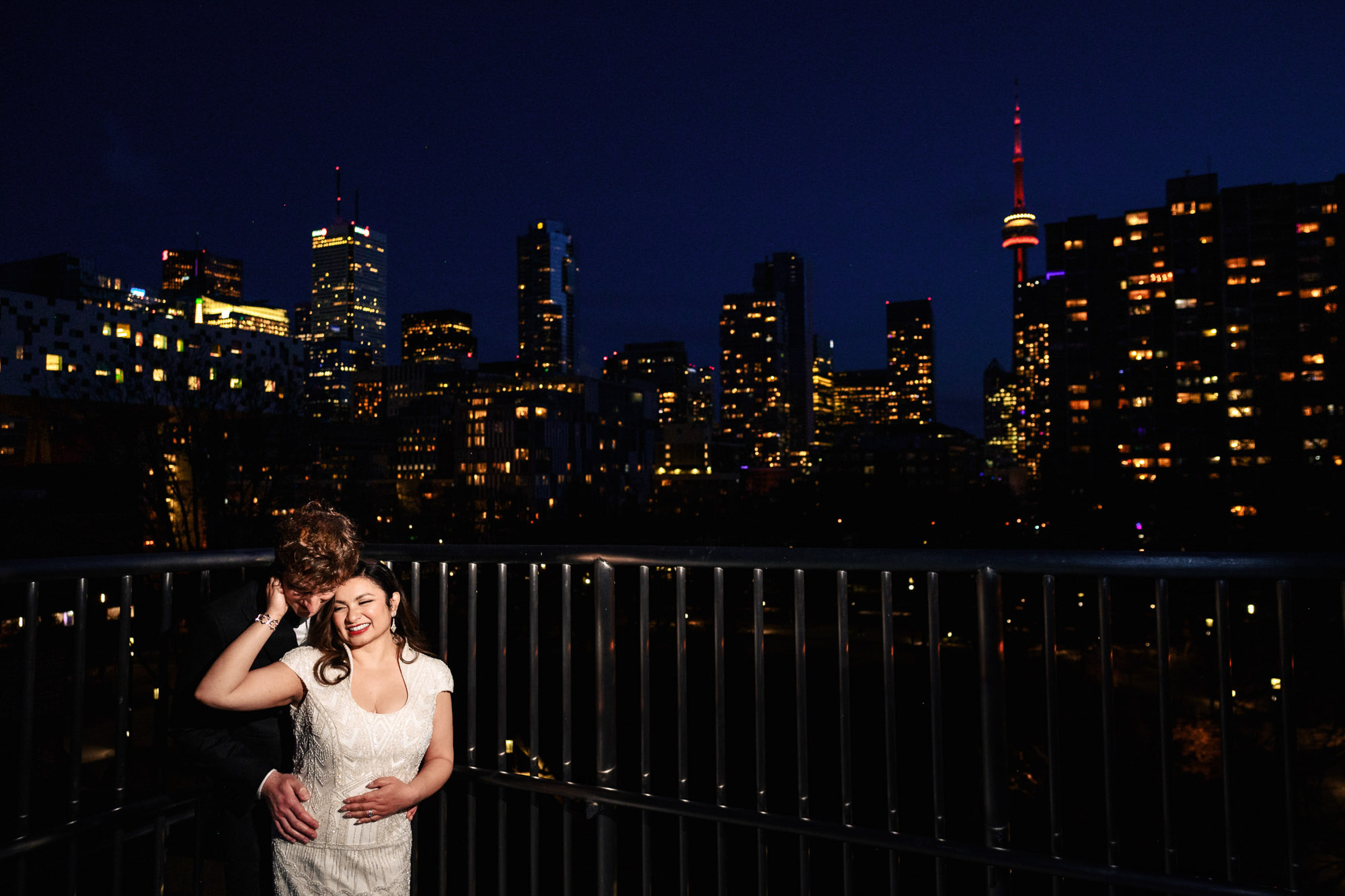 A couple embracing on a balcony at night, city skyline—a perfect Art Gallery of Ontario wedding.