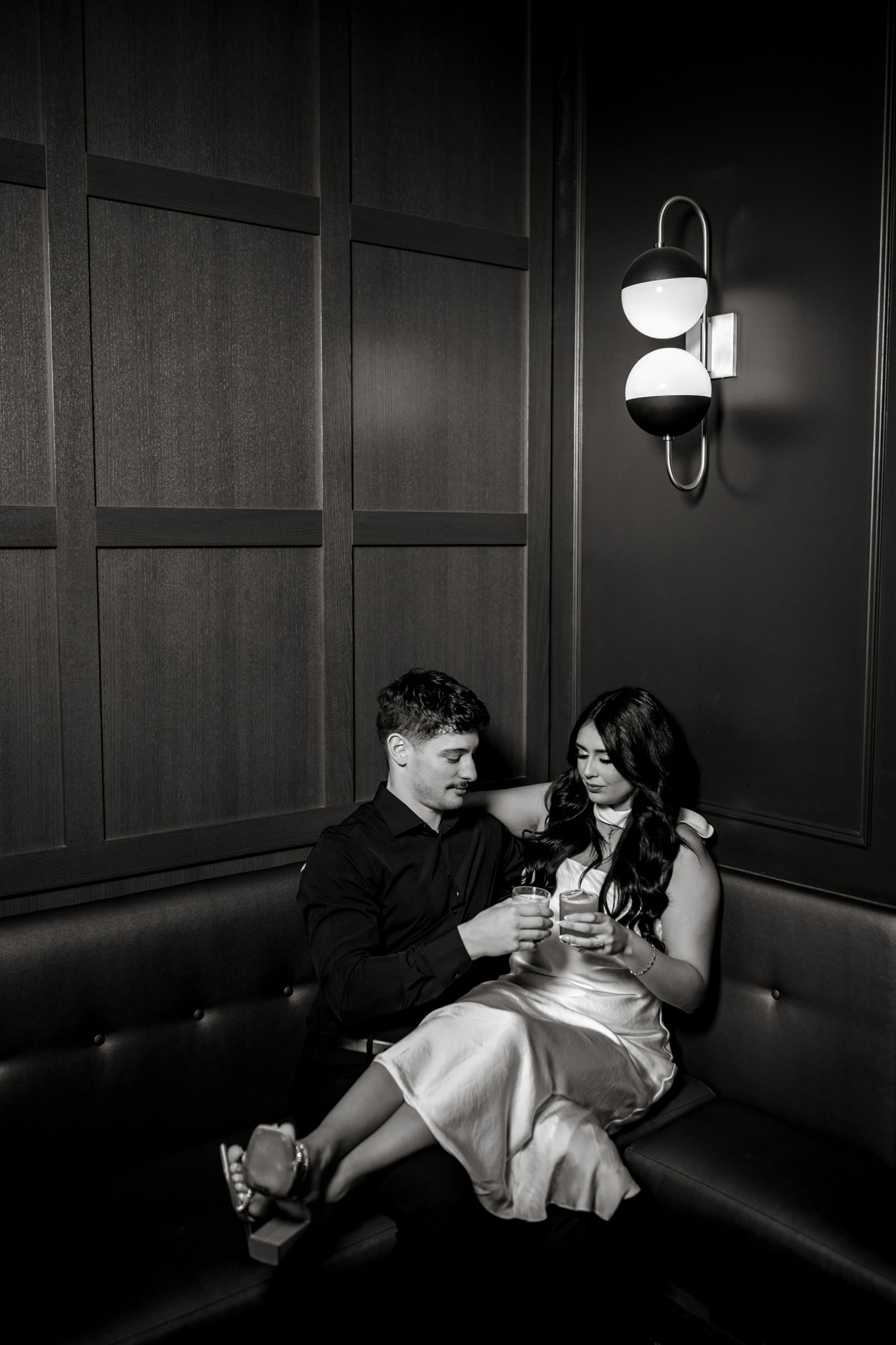 In a dim Winnipeg room, a couple in love, glasses in hand, gaze at each other.