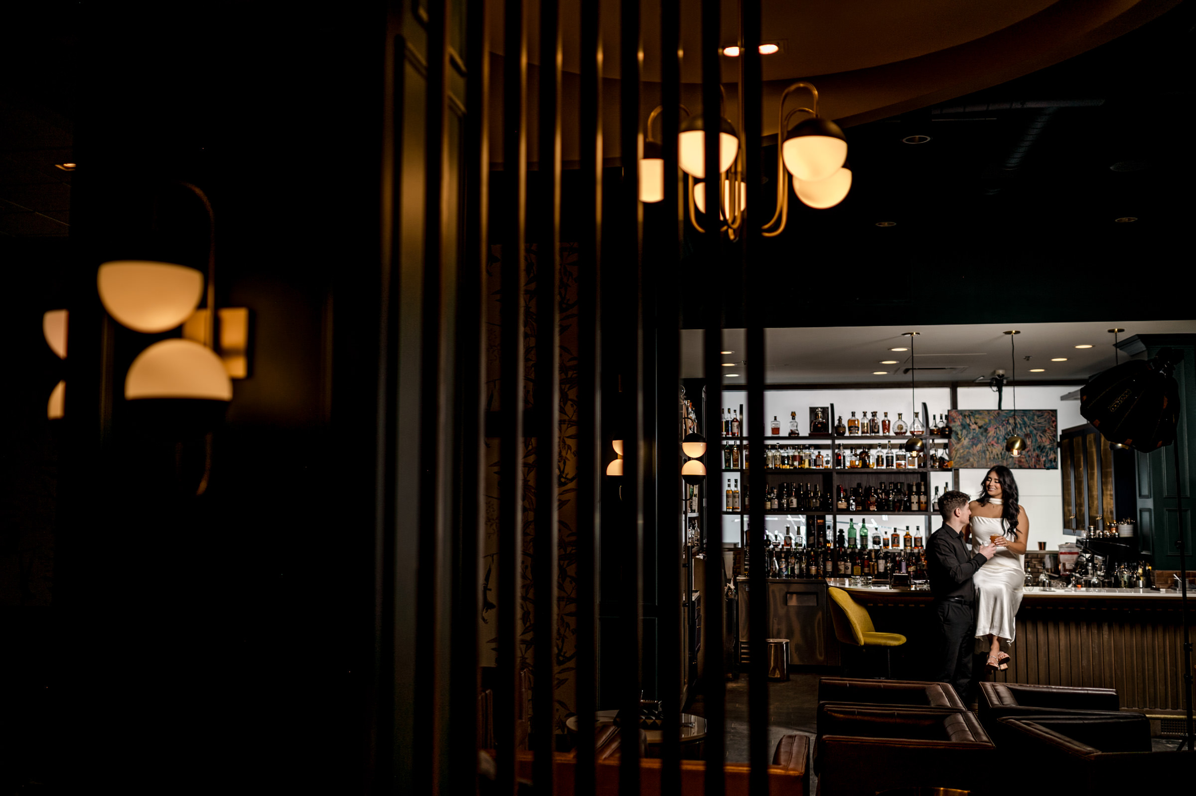 A couple sits at the dimly lit bar, a cozy spot perfect for a Winnipeg engagement.