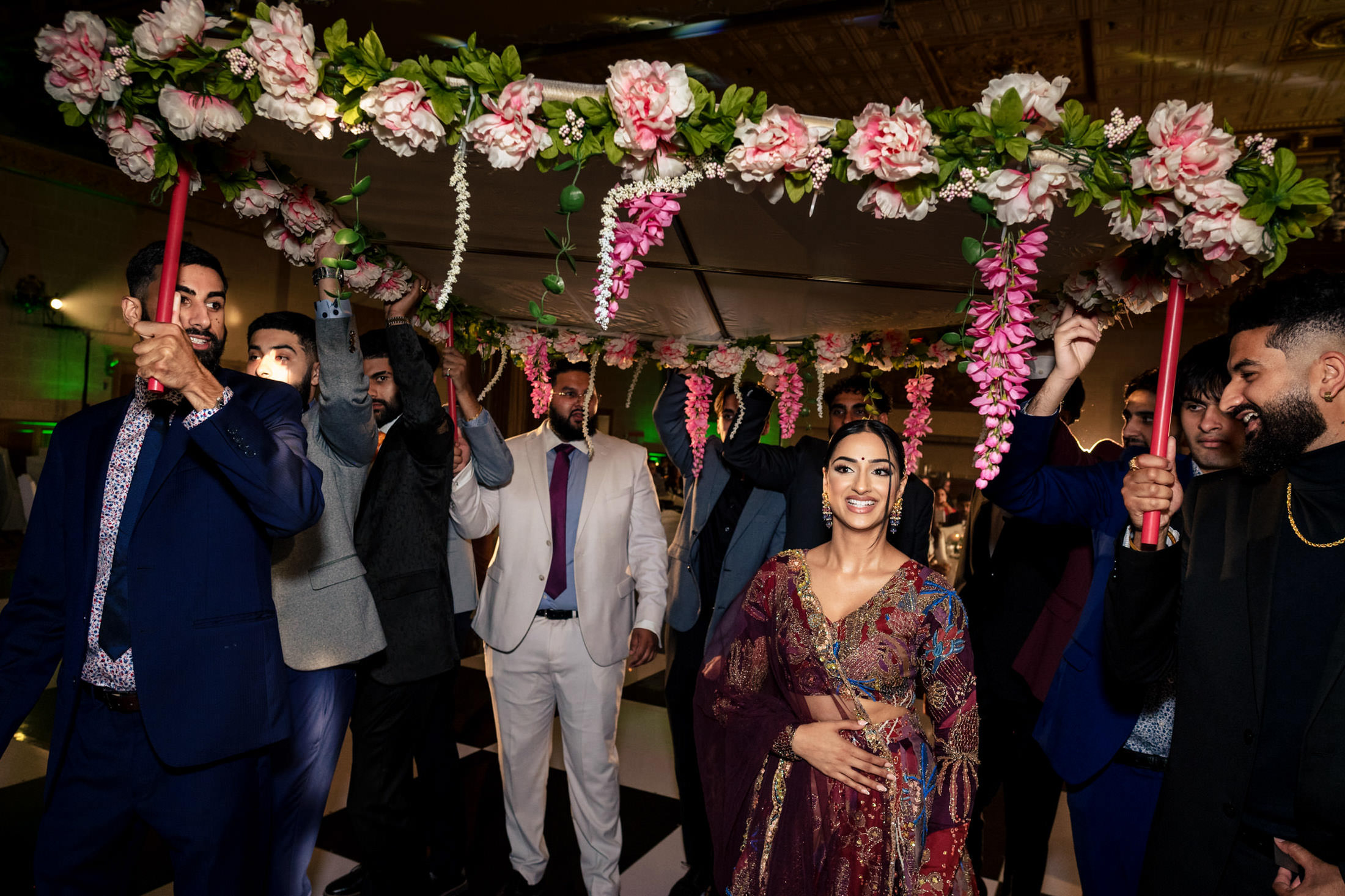 A woman in colorful attire walks under a floral canopy at a vibrant Winnipeg wedding.