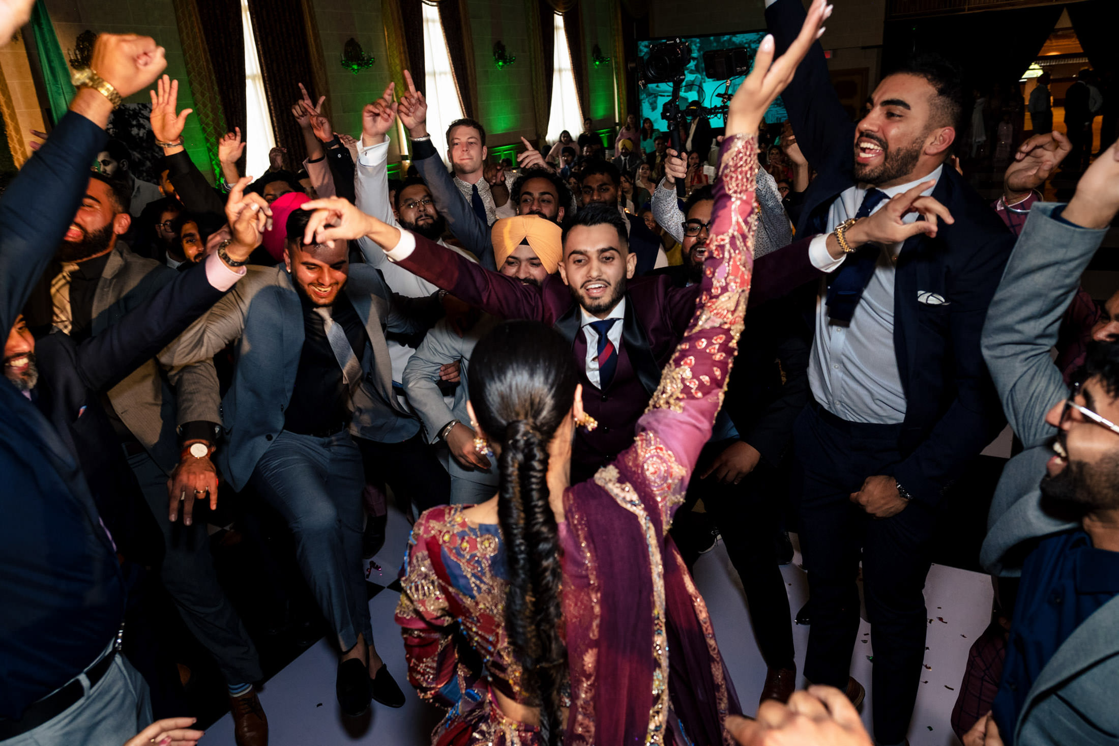 People joyfully dancing in formal attire at a lively Winnipeg wedding celebration.