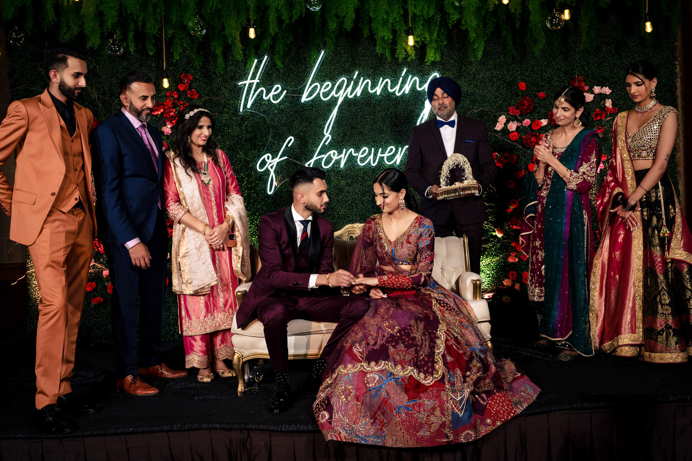 Couple seated on stage, surrounded by elegant guests and florals at a Winnipeg wedding.