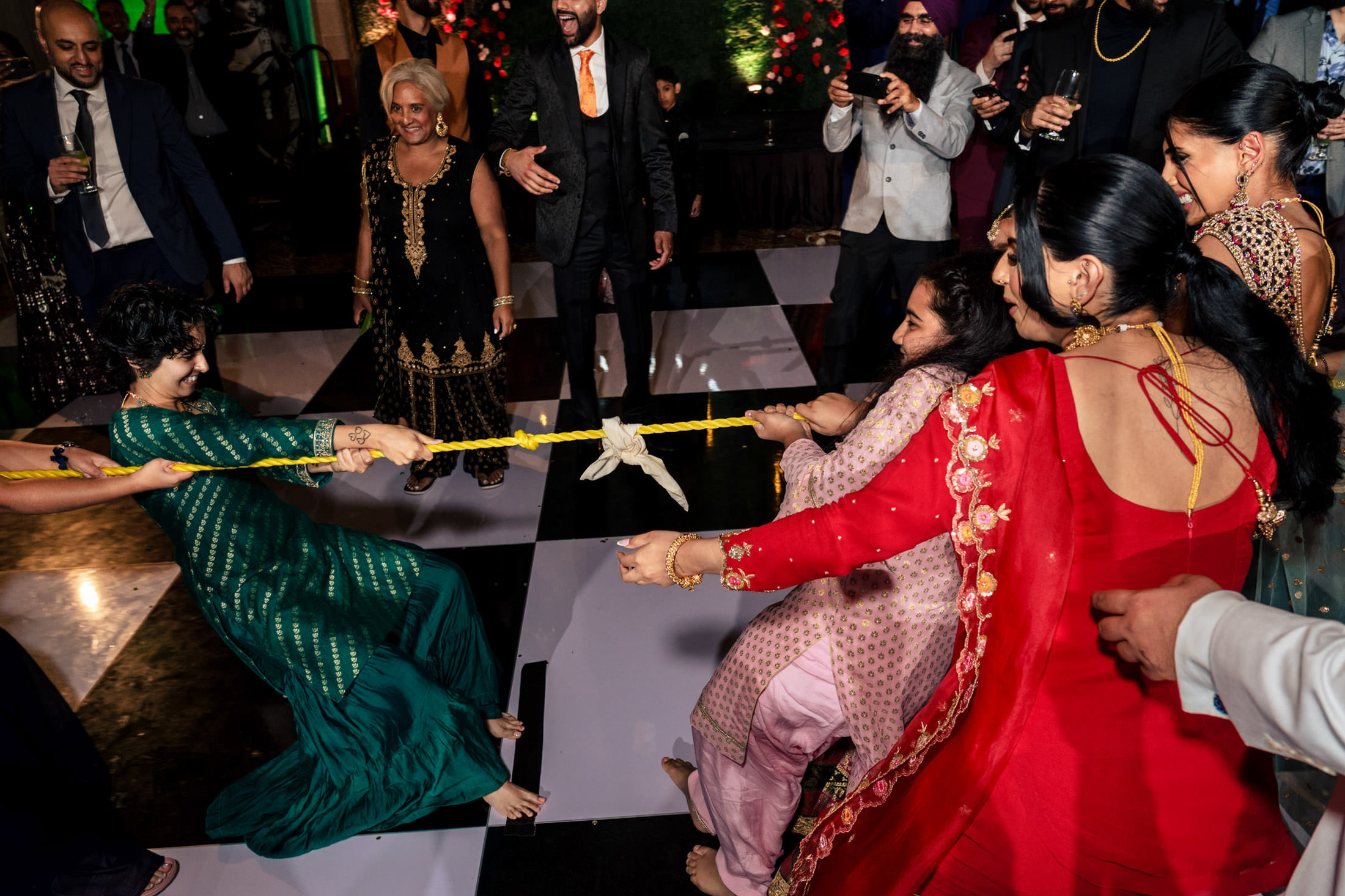People at a Winnipeg wedding enjoy a lively indoor tug-of-war, surrounded by onlookers.