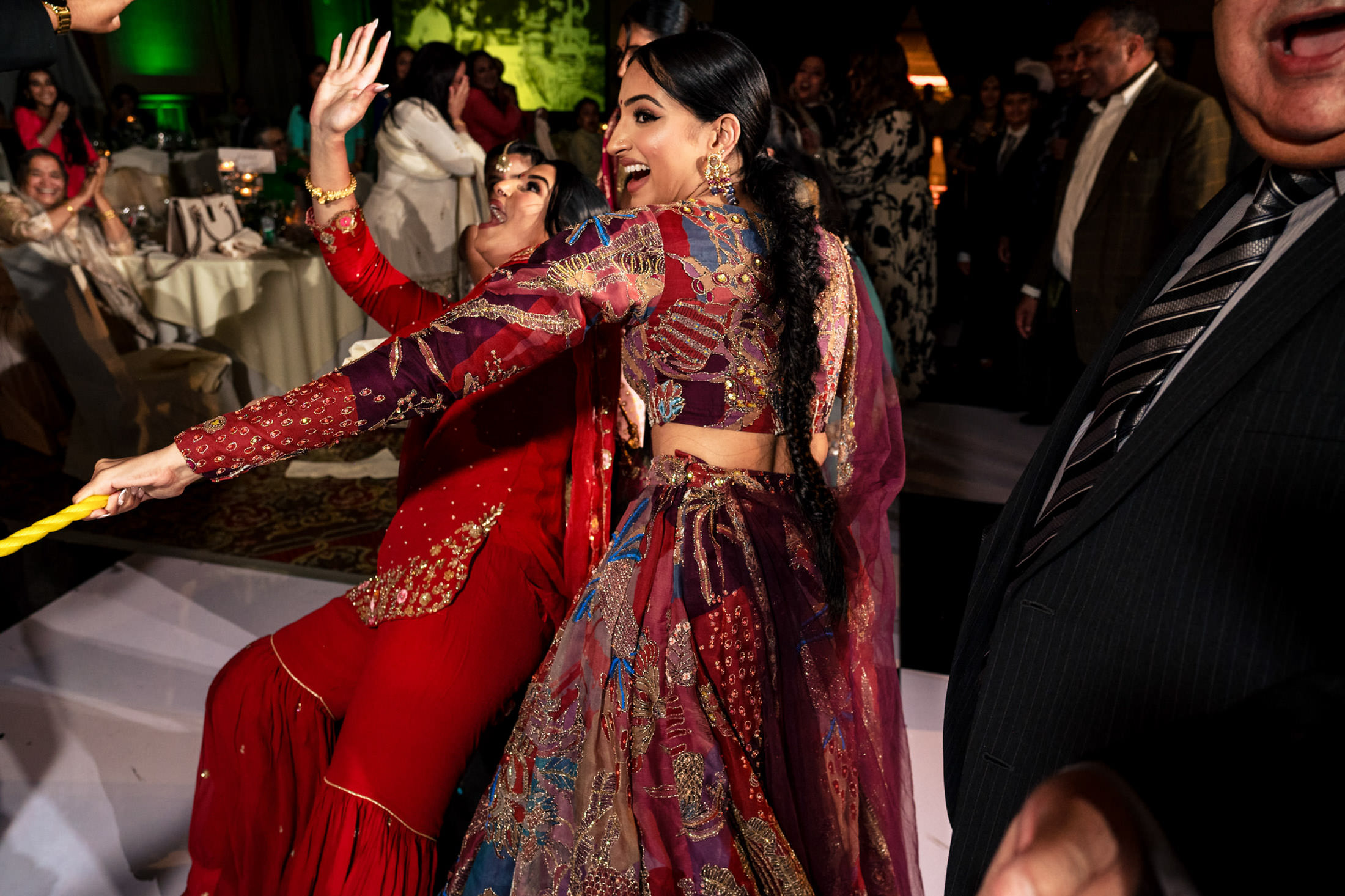 Two people in vibrant traditional attire dance joyfully at an indoor Winnipeg wedding.